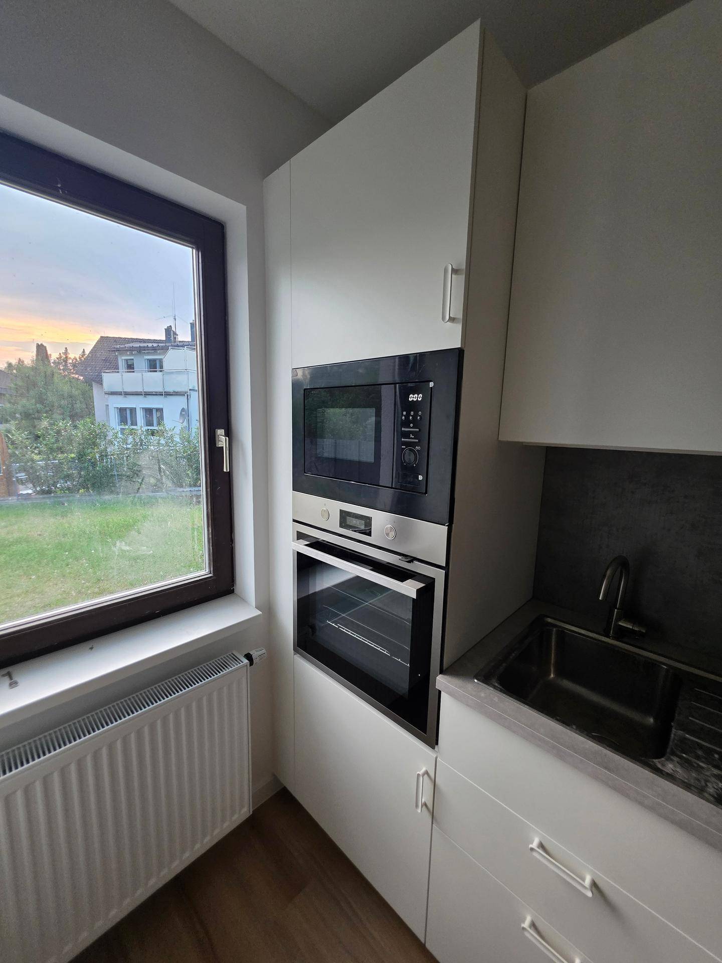 Integrierter Backofen und Mikrowelle in der modernen Küche mit Fensterblick.