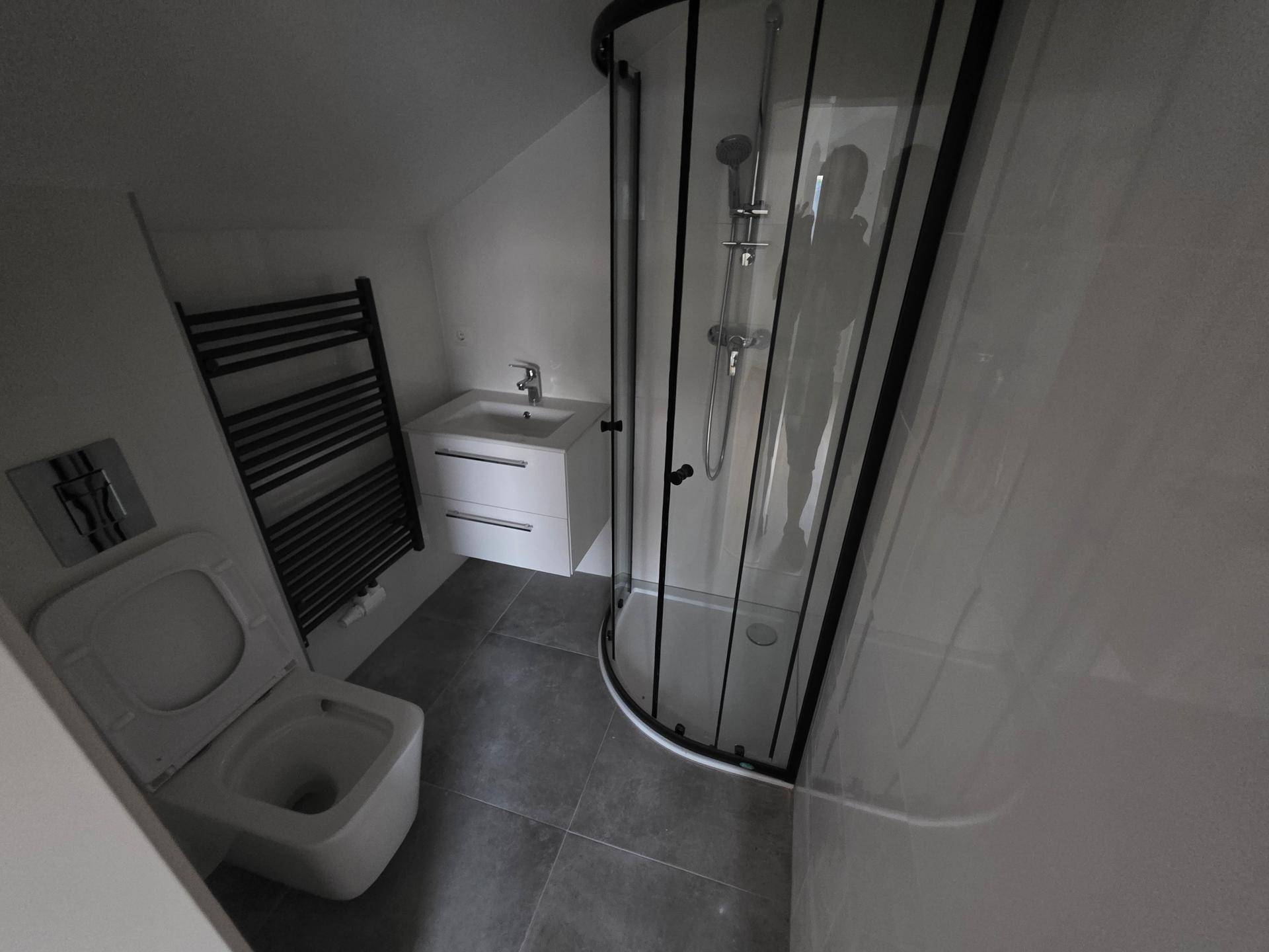 Modernes Badezimmer im Dachgeschoss mit Duschkabine, Waschtisch, WC und beheiztem Handtuchhalter.