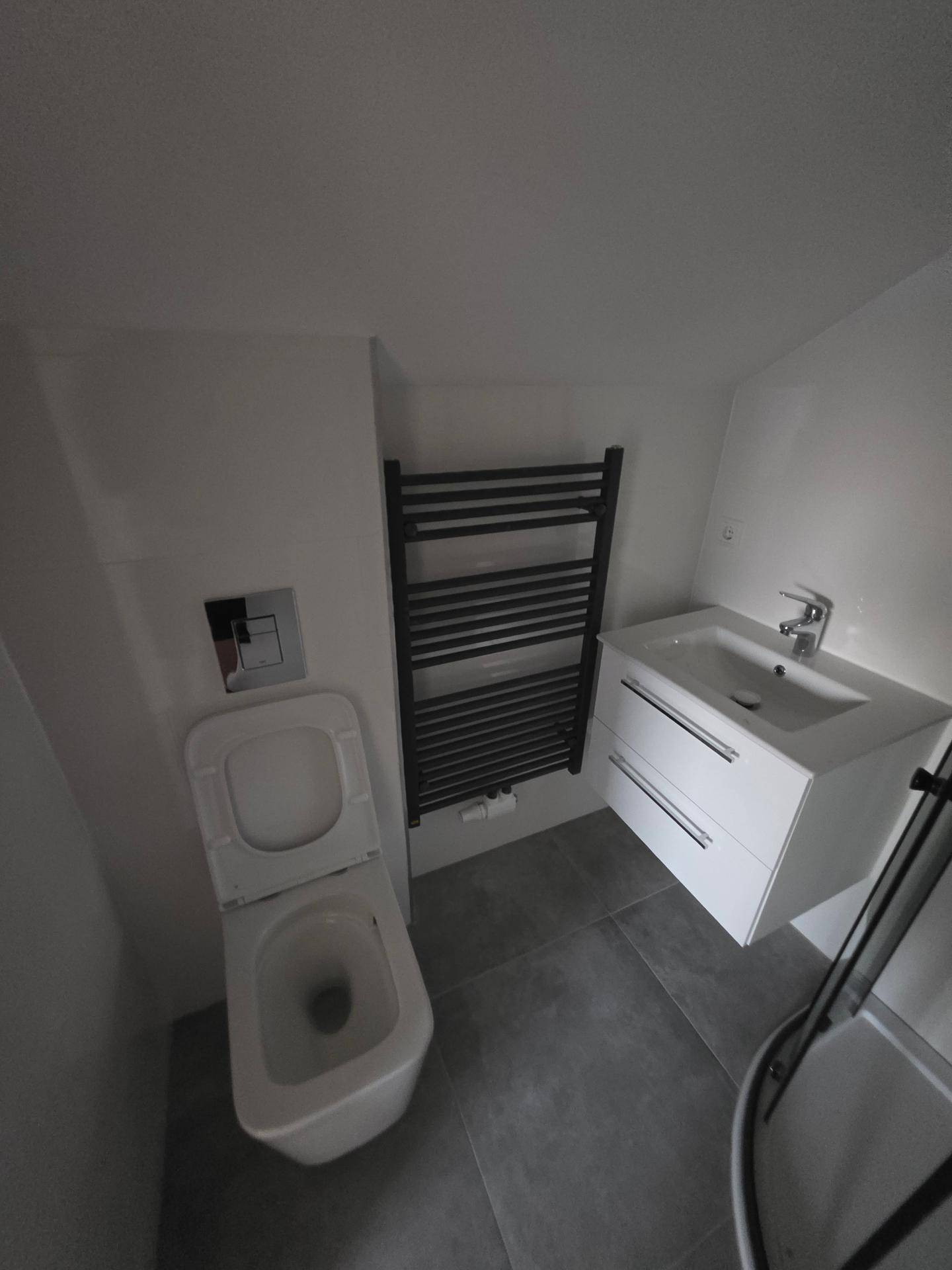 Modernes Badezimmer mit wandhängendem WC, Waschtisch und beheiztem Handtuchhalter.