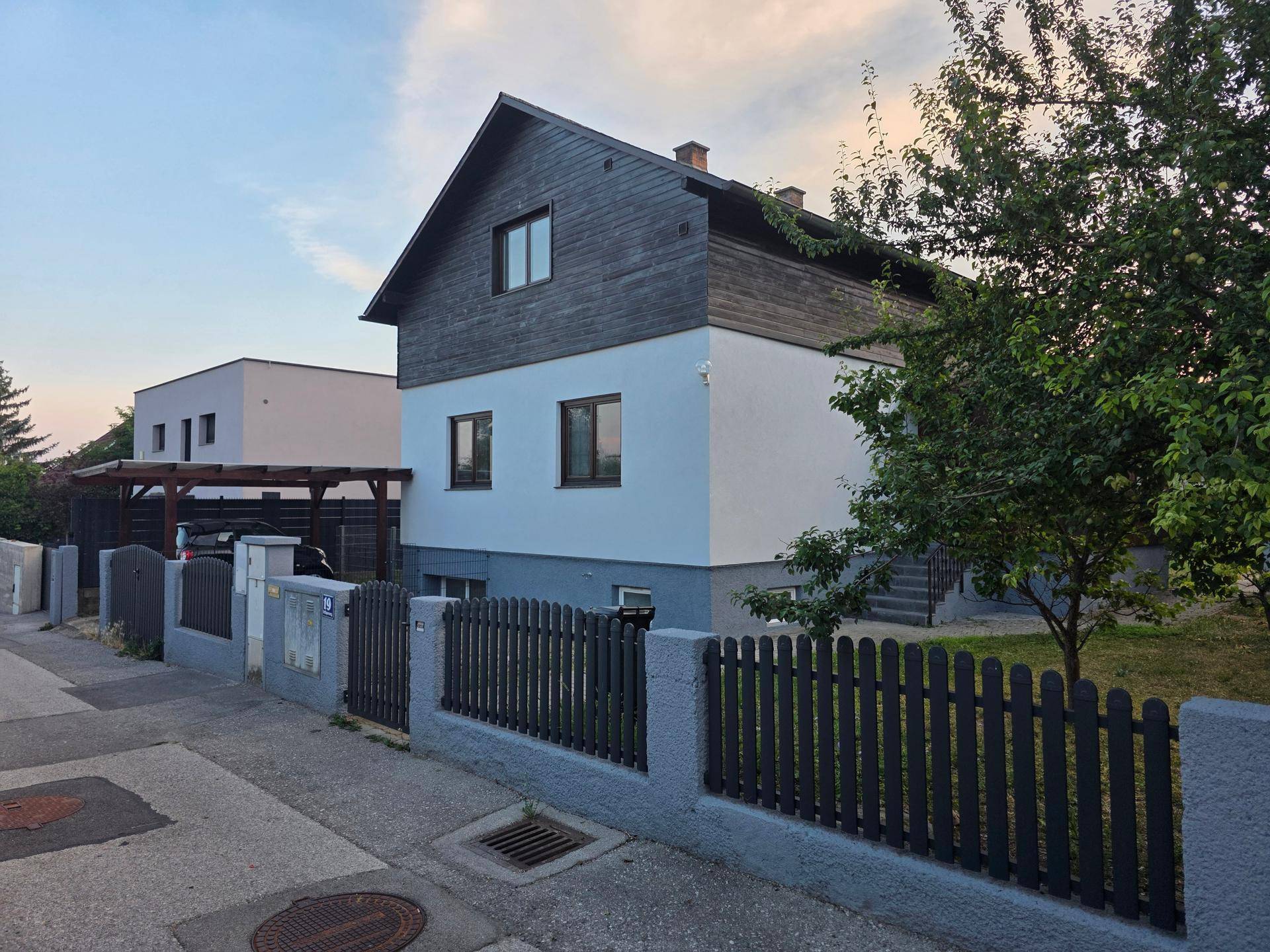 Einfamilienhaus mit ansprechender Architektur, Holzelementen und umzäuntem Vorgarten.