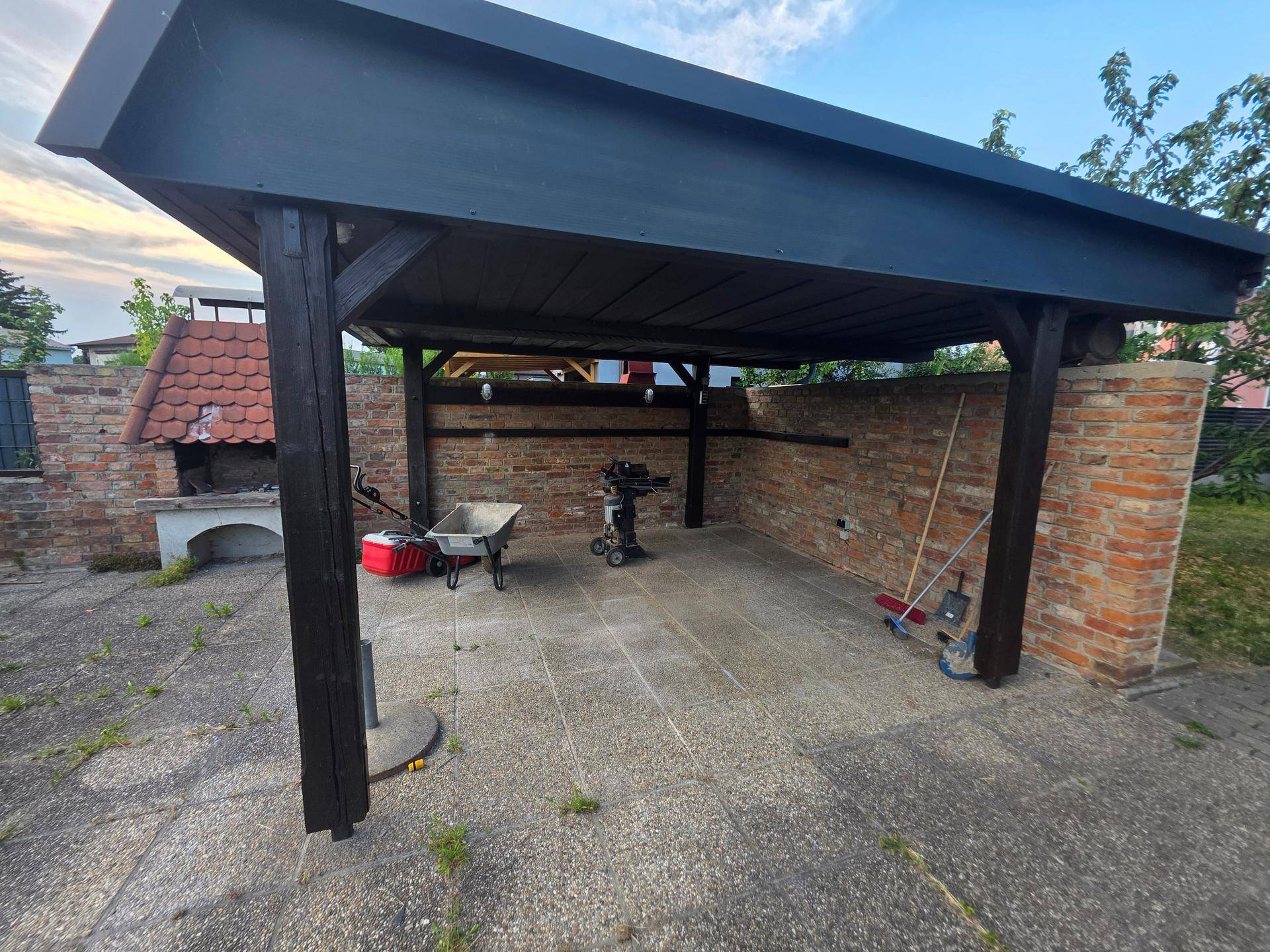 Überdachter Terrassenbereich mit Holzbalken und gemauerter Wand, ideal für Outdoor-Aktivitäten.