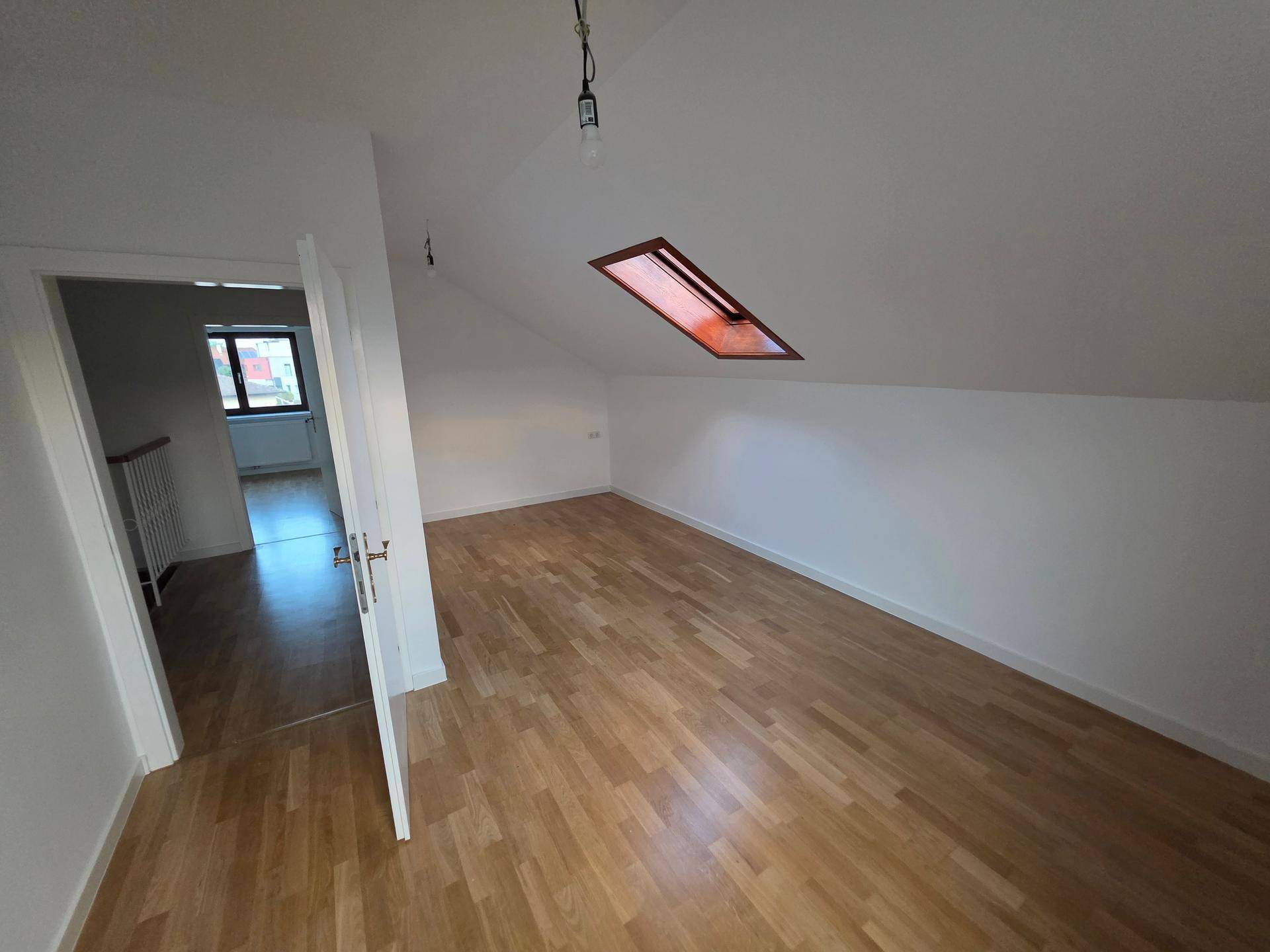 Helles Schlafzimmer im Dachgeschoss mit Holzboden und Dachfenster, bietet viel Tageslicht.