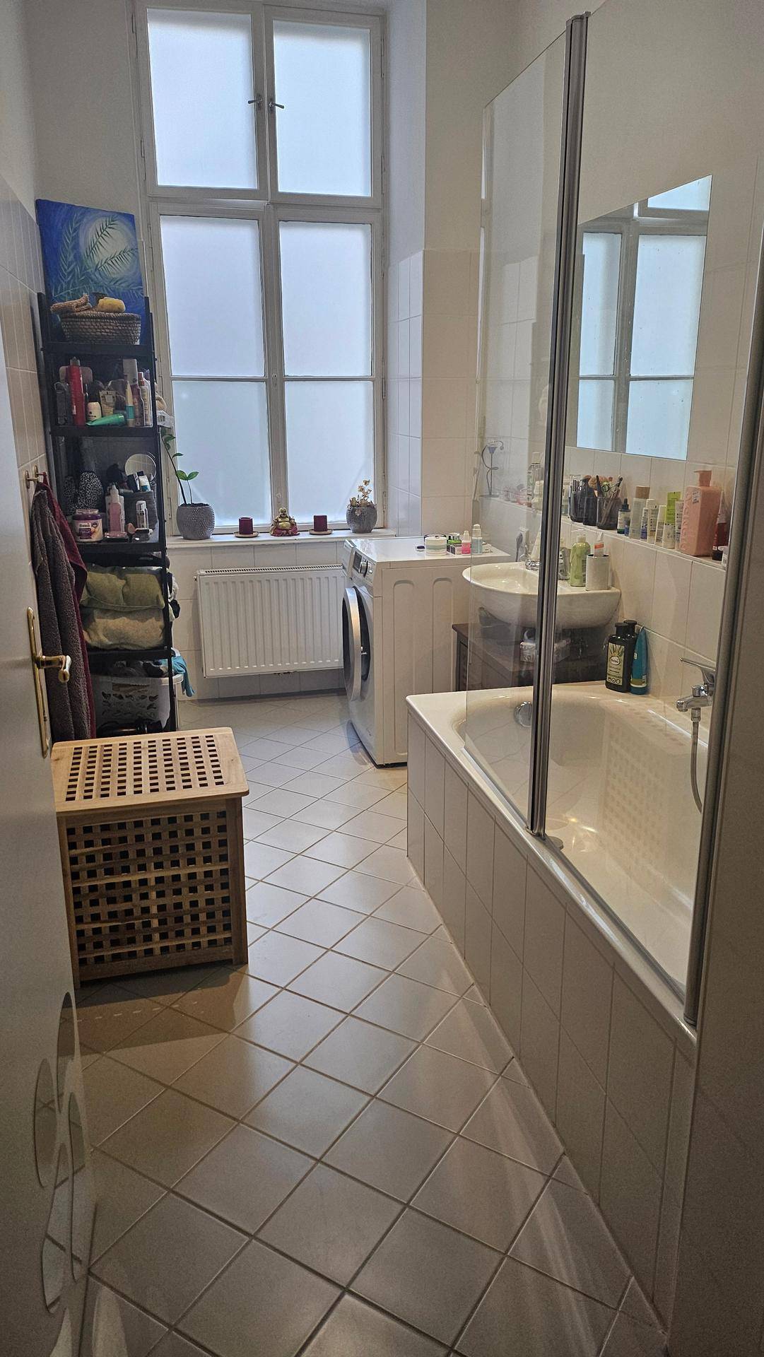 Helles Badezimmer mit Badewanne, Waschmaschine und gefliestem Boden.