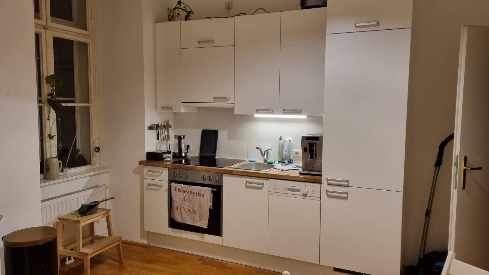 Moderne Küchenzeile mit weißen Schränken, Kochfeld, Spüle und Geschirrspüler.