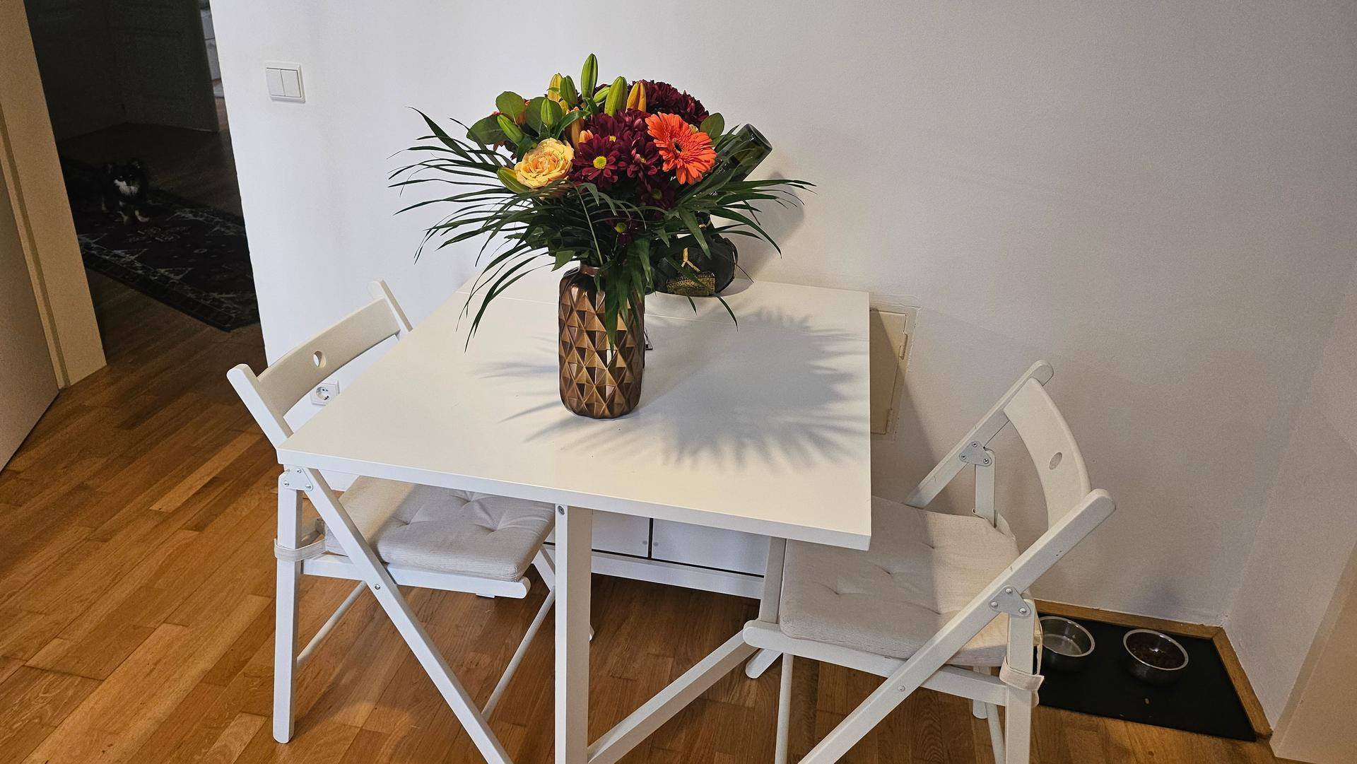 Kleiner Esstisch mit zwei Stühlen und einem Blumenstrauß in der Küche.