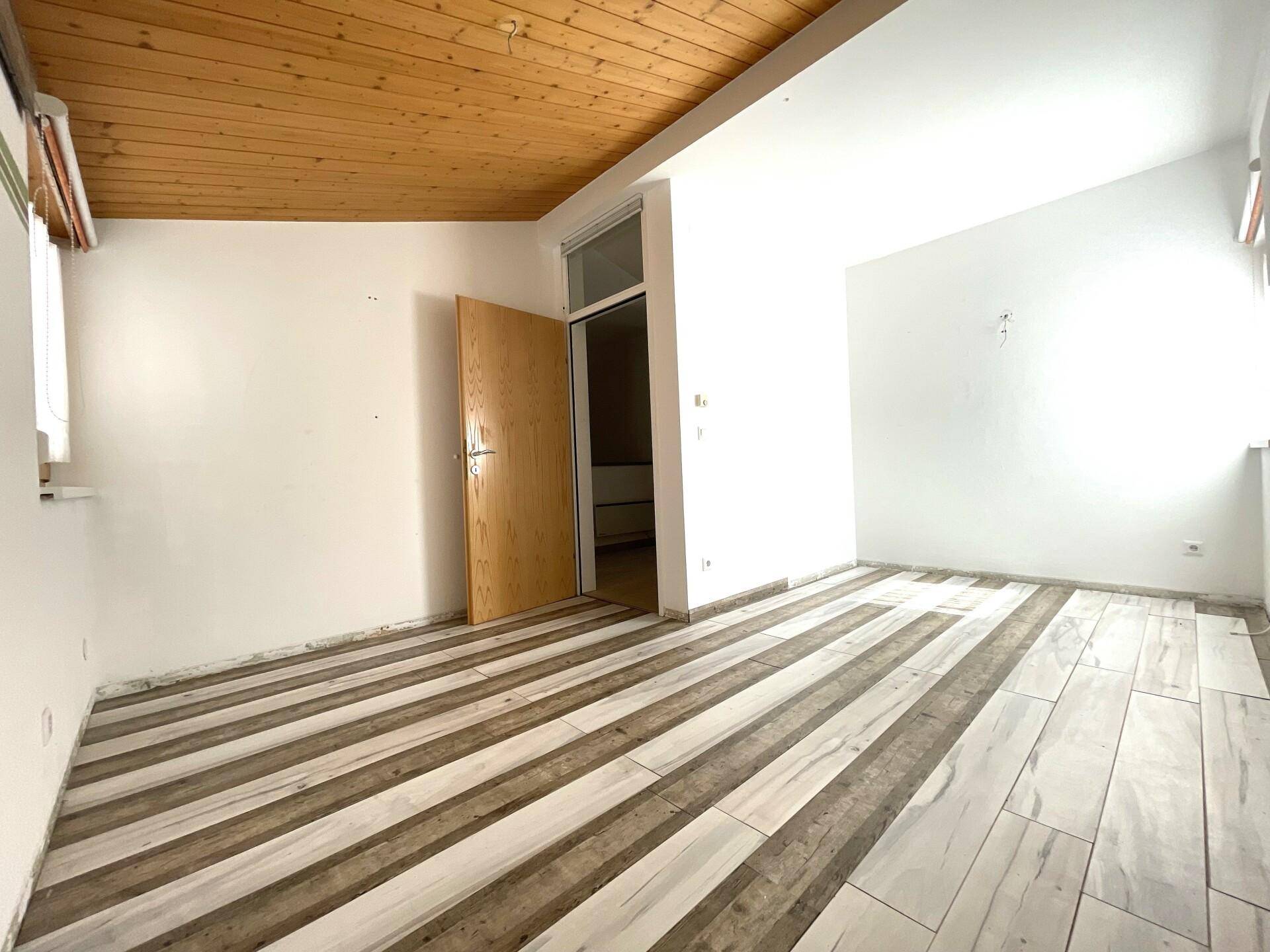 Schlafzimmer mit Holzbalkendecke und modernem Bodenbelag, bietet eine gemütliche Atmosphäre.
