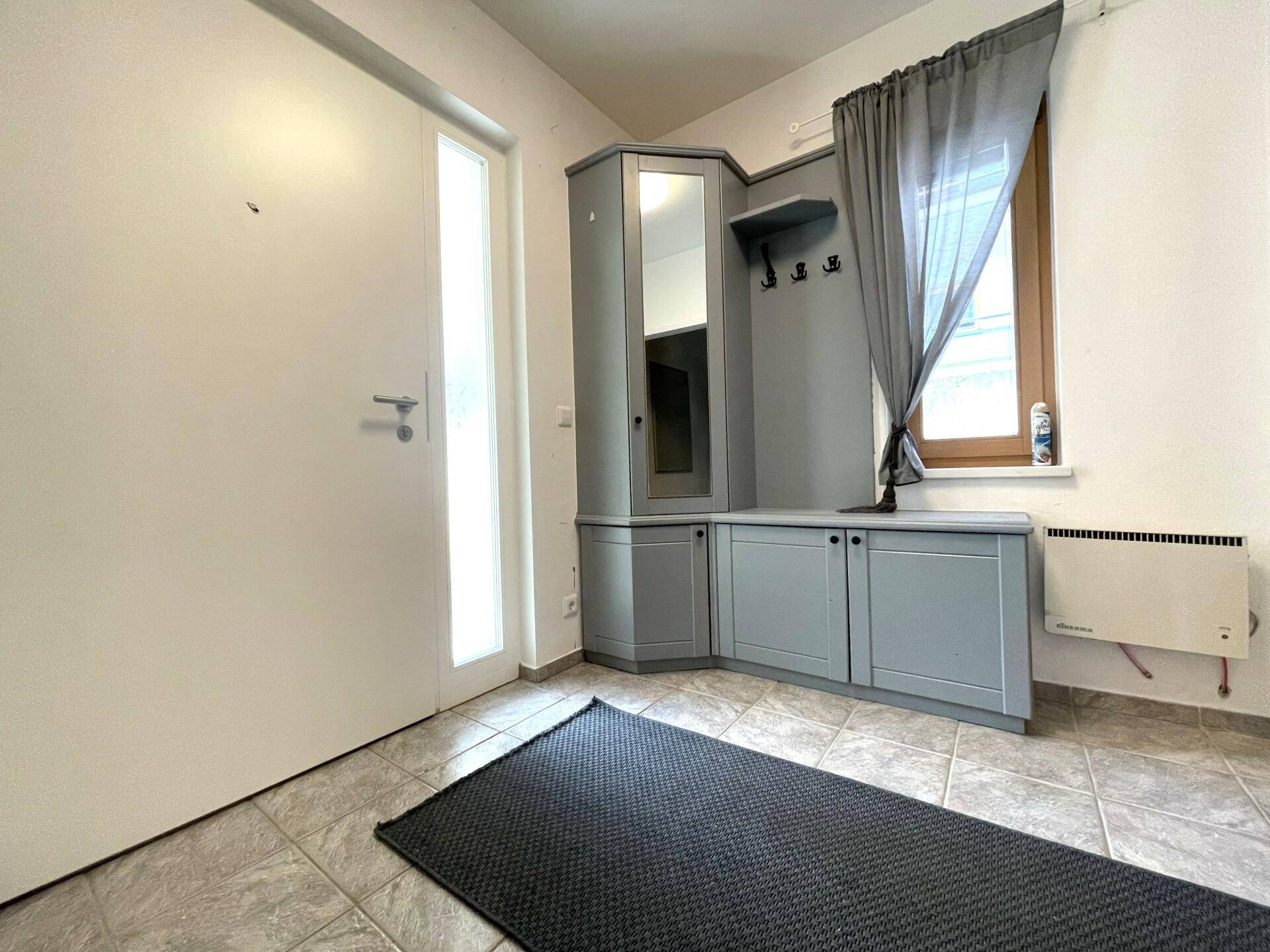 Eingangsbereich mit Fliesenboden und einer praktischen Garderobe mit Spiegel.