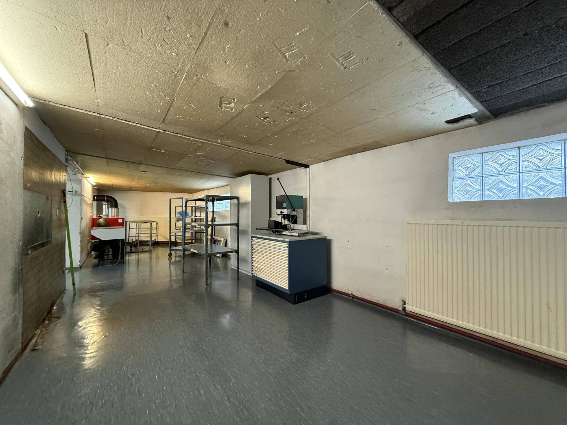 Lagerraum im Untergeschoss mit Betonboden, Heizkörper und einem kleinen Fenster mit Glasbausteinen.