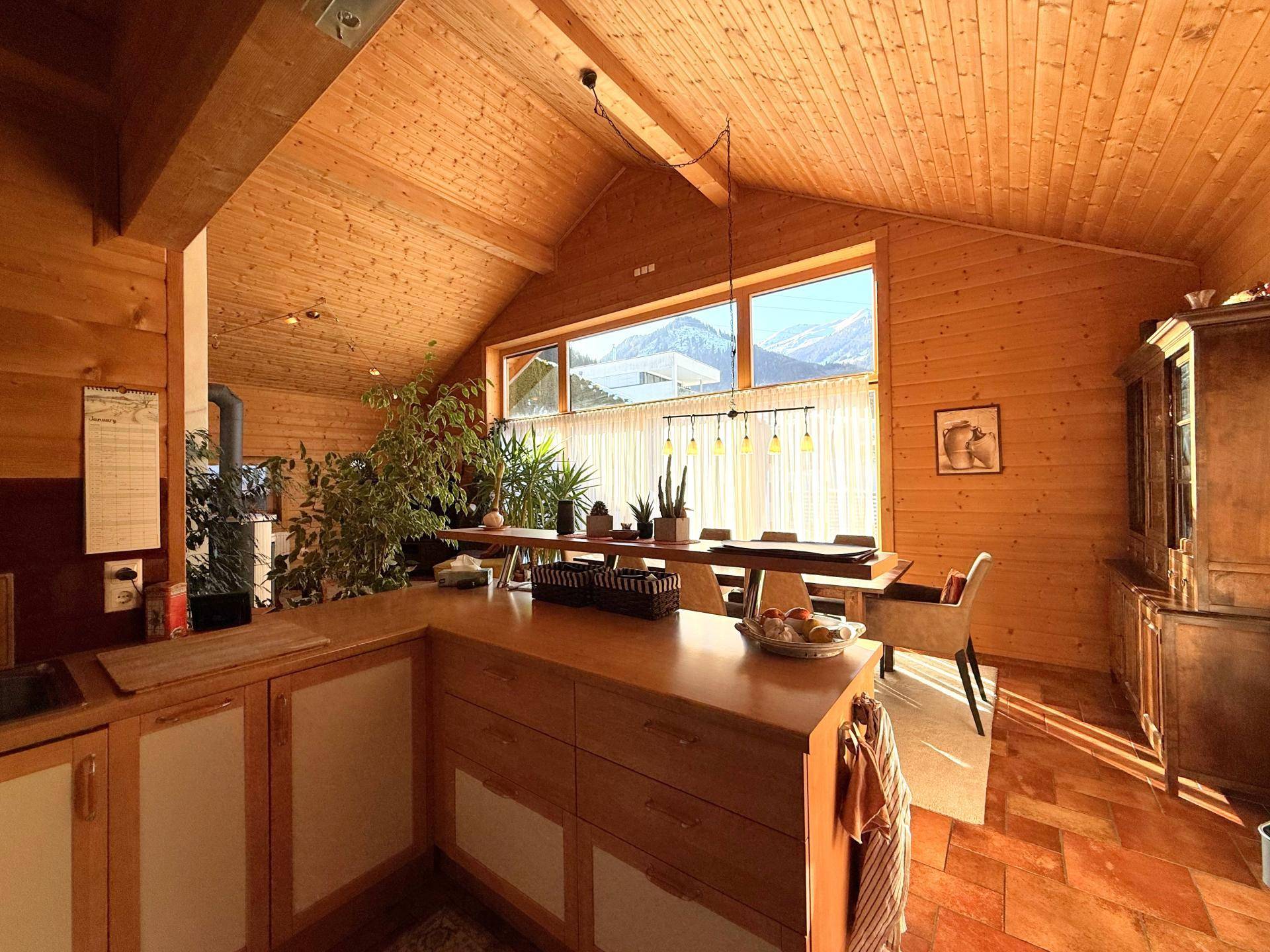 Moderne Holzküche mit Kochinsel und Essbereich, der einen weiten Blick auf die Berge bietet.