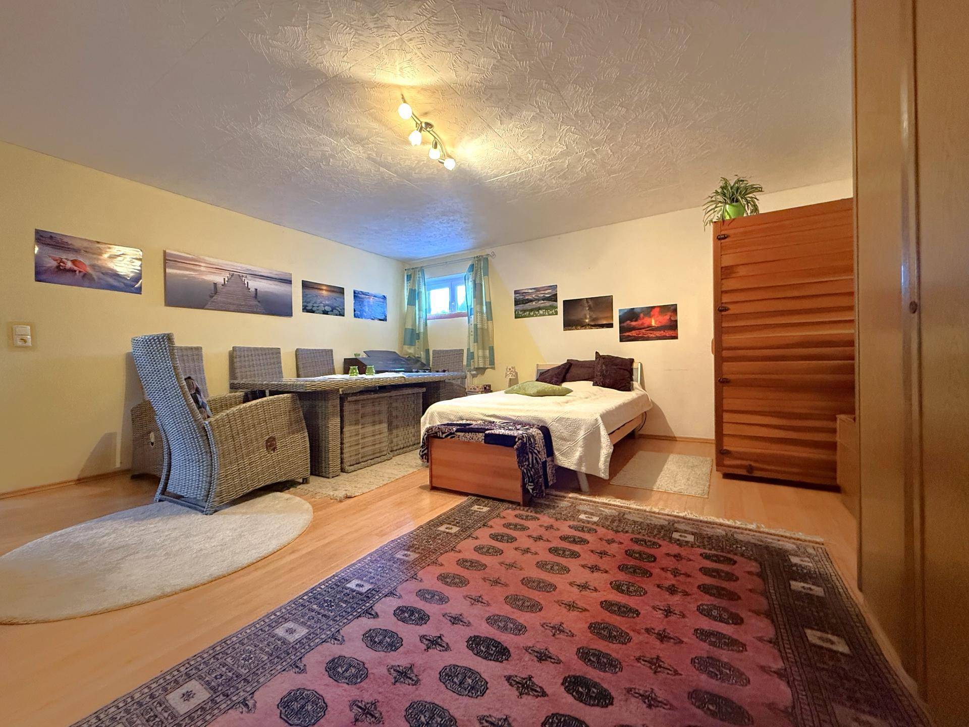 Geräumiges Schlafzimmer mit Laminatboden, Doppelbett und Essbereich, vielseitig nutzbar.
