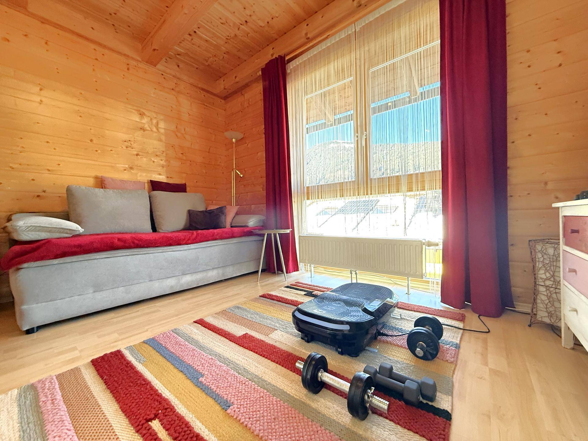 Helles Schlafzimmer mit Holzwänden, Sofa und Fitnessgeräten, ideal als Gäste- oder Sportzimmer.