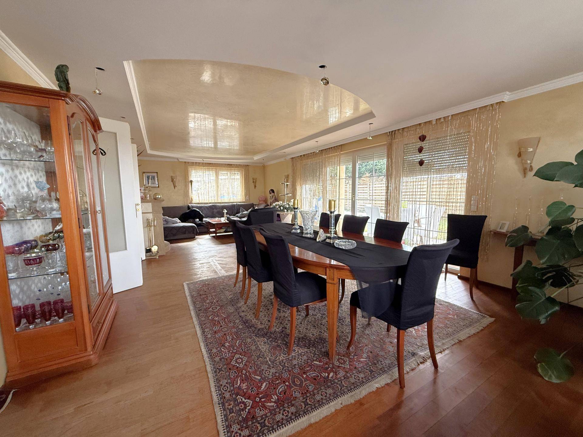 Geräumiger Wohn-Essbereich mit Holzboden, großem Esstisch und Zugang zur Terrasse.