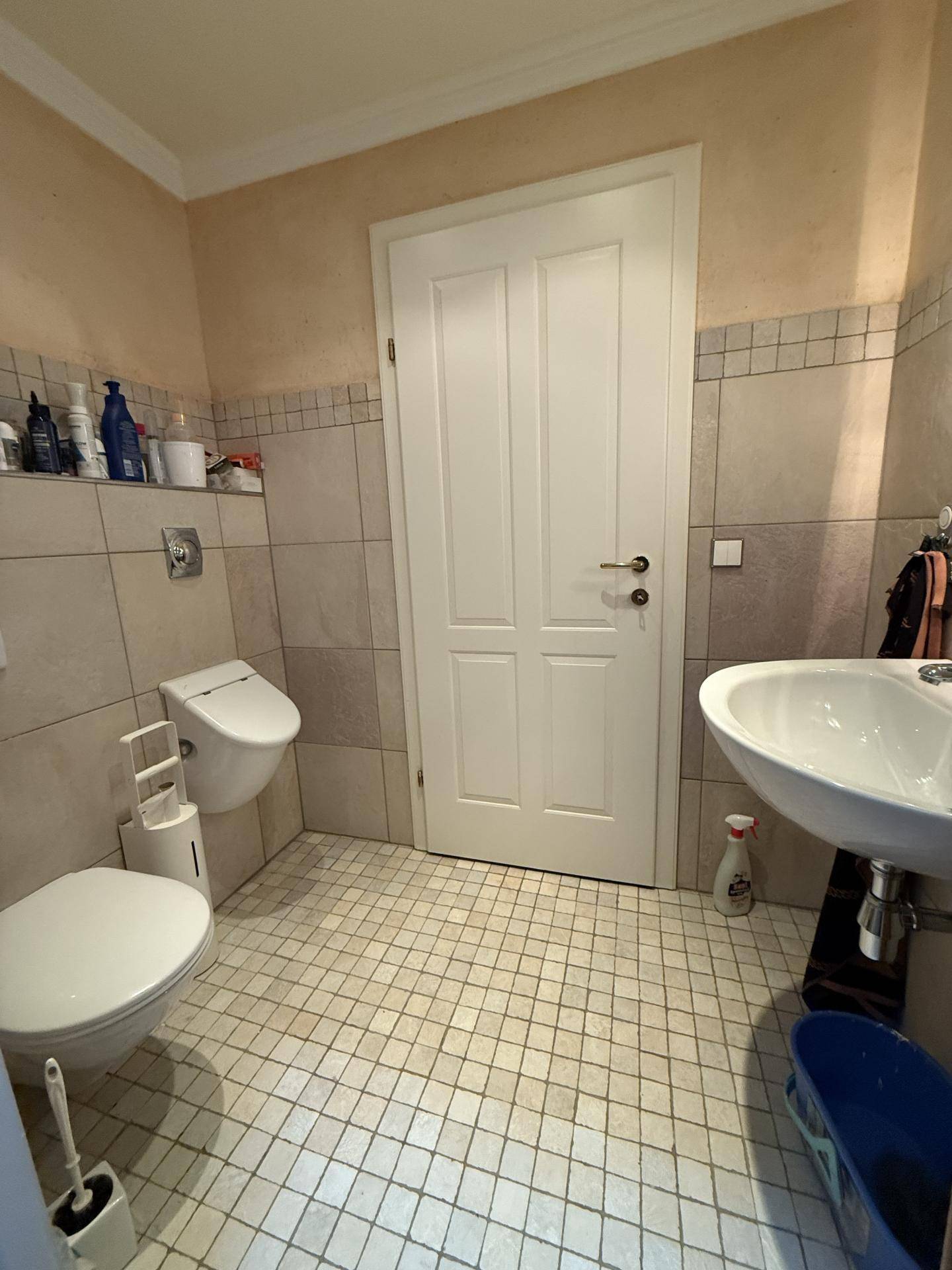 Helles Gäste-WC mit Wand-WC, Waschbecken und hellen Fliesen.