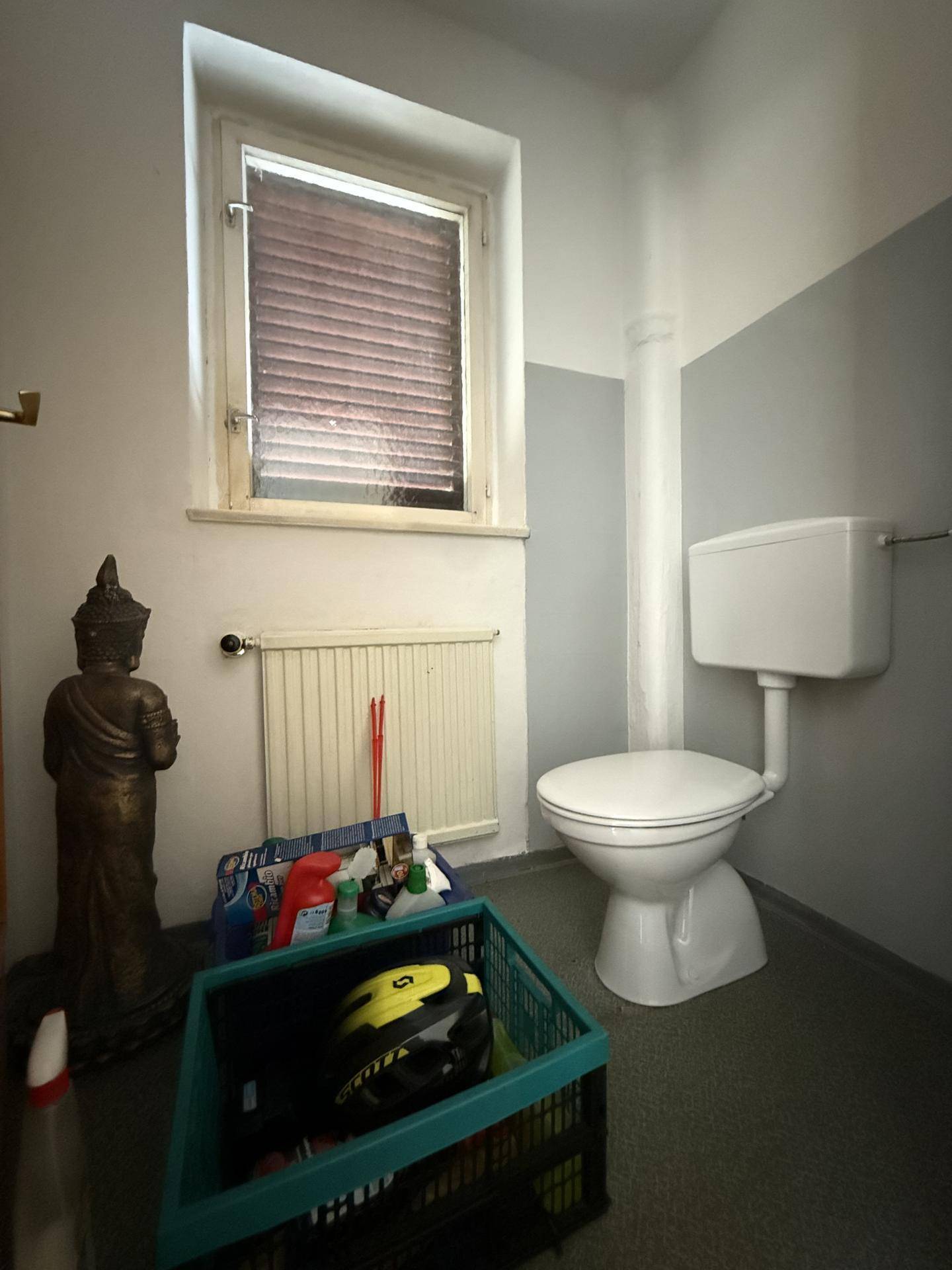 Separates WC mit Fenster, Heizung und einfacher Ausstattung.