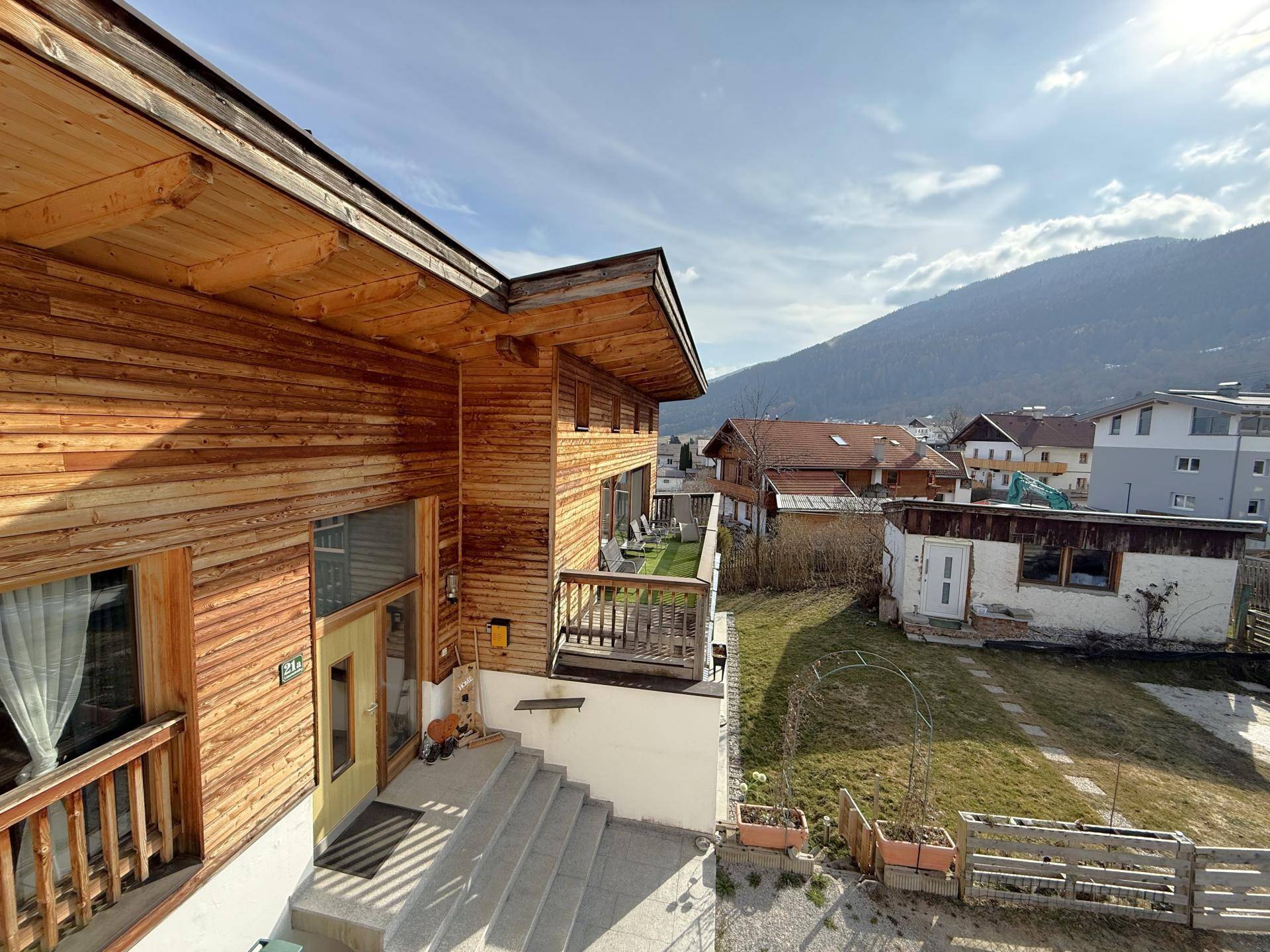 Ansicht des Hauses mit Holzfassade und Bergpanorama im Hintergrund, moderne Architektur.