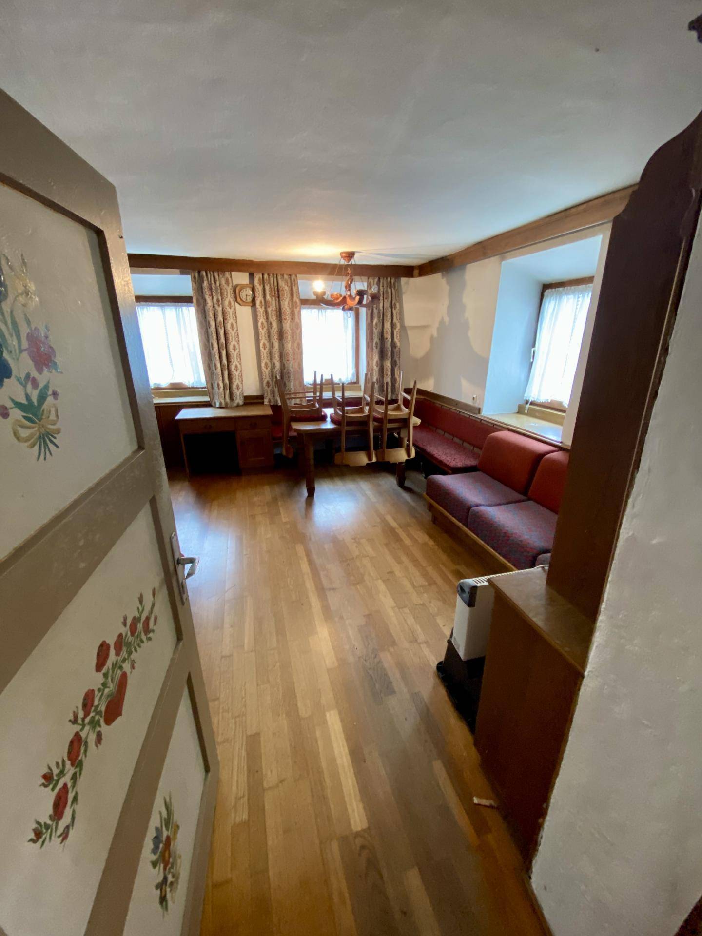 Gemütlicher Wohn-Essbereich mit Holzboden, traditionellen Möbeln und Fenstern.
