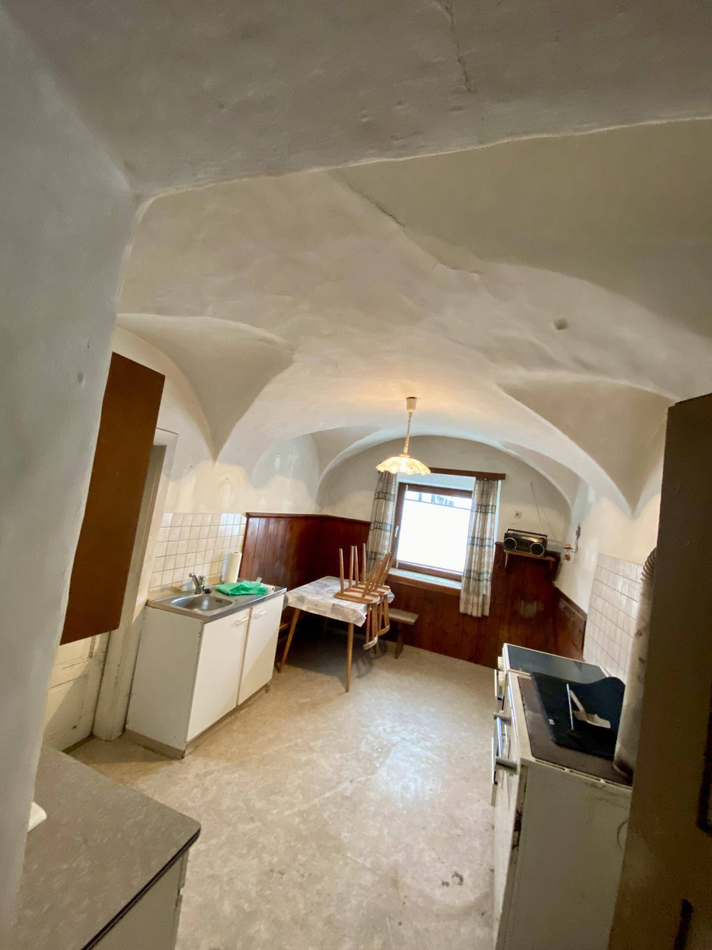 Rustikale Küche mit Gewölbedecke, einfachen Küchenmöbeln und einem Fenster.