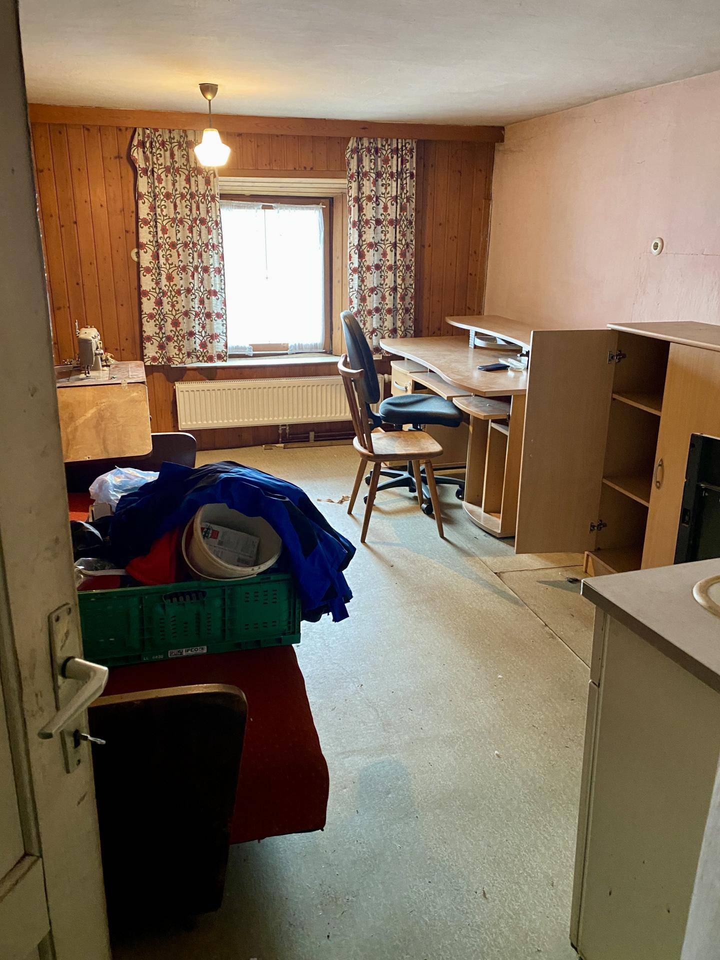 Schlafzimmer mit Holzvertäfelung, Schreibtisch und Fenster.