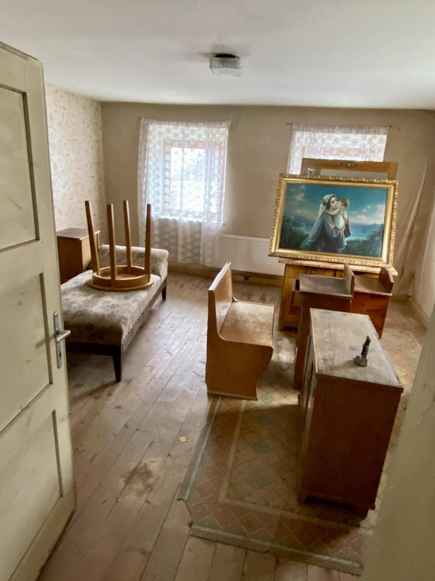 Schlafzimmer mit Holzboden, Tagesbett und einem großen Gemälde.