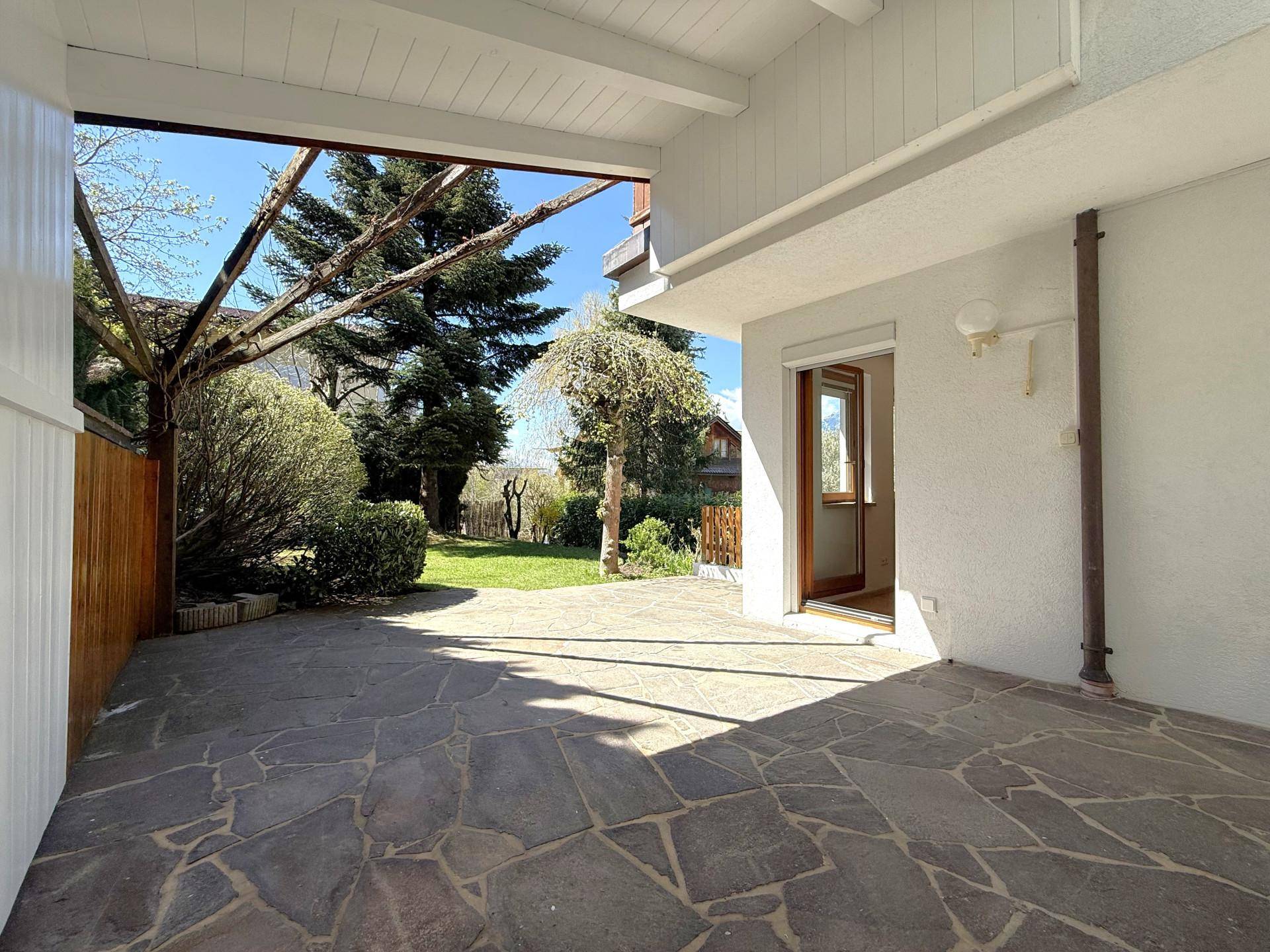 Überdachte Terrasse mit Natursteinboden und Zugang zum grünen Gartenbereich, ideal für entspannte Stunden.