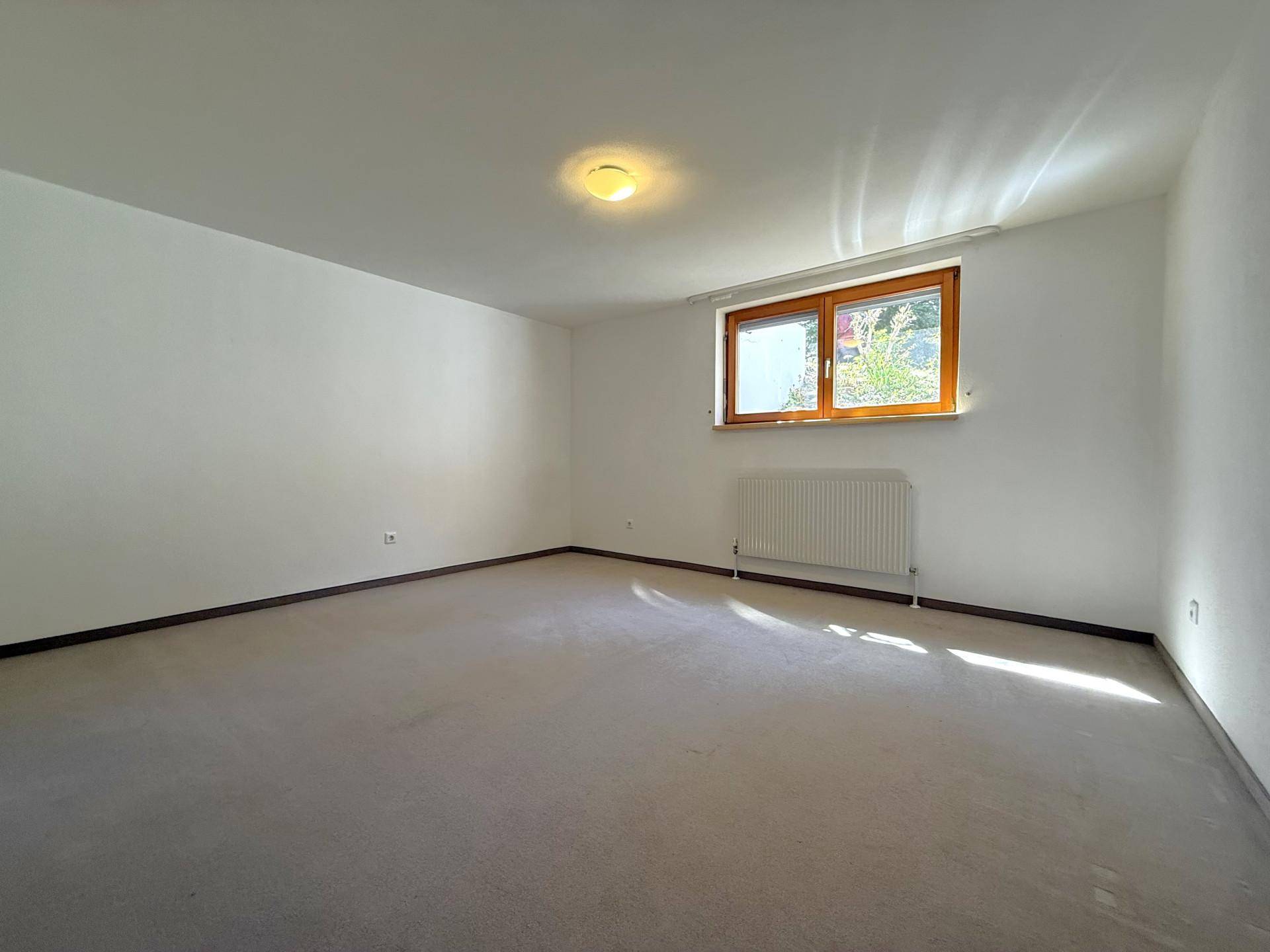 Helles Zimmer mit Teppichboden und einem Fenster, das viel Tageslicht hereinlässt, vielseitig nutzbar.