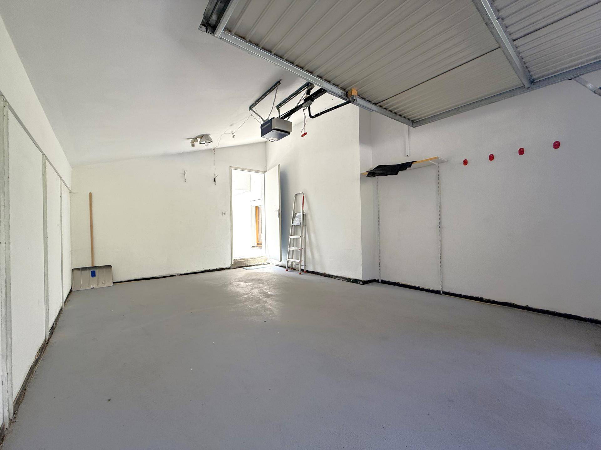 Geräumige Garage mit Betonboden und automatischem Toröffner, bietet Platz für Fahrzeuge.