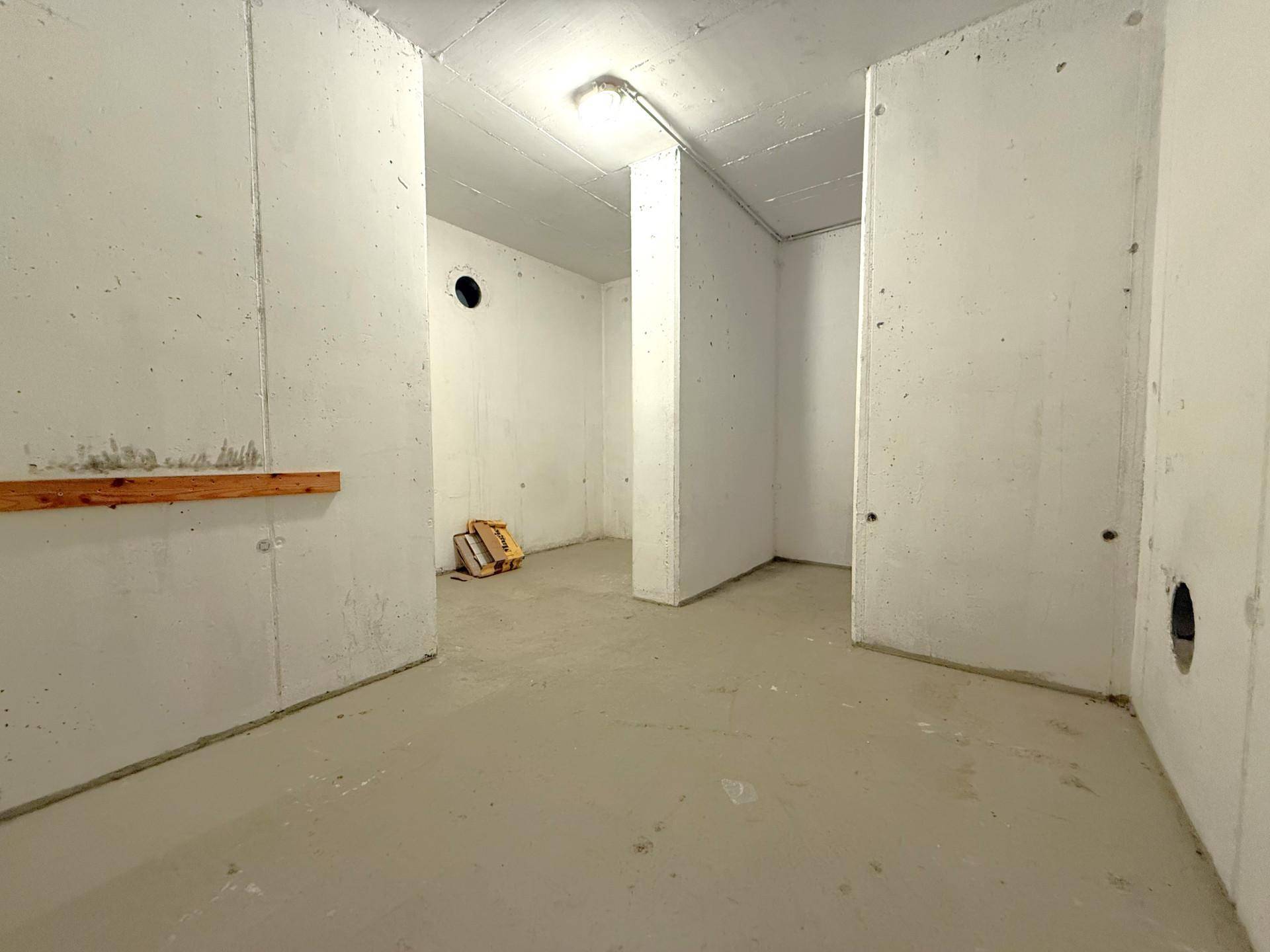 Unausgebauter Kellerraum mit Betonwänden und -boden, ideal als Lager- oder Abstellfläche.