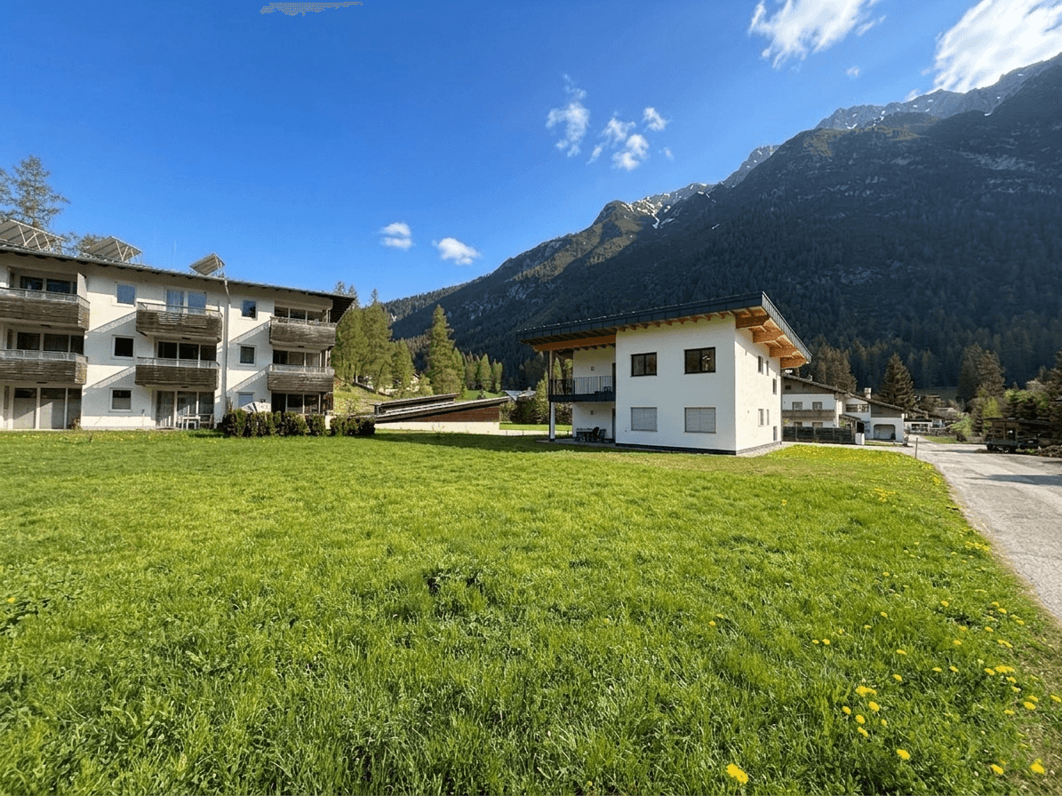 Modernes Gebäude mit Holzdach und weitem Blick auf die umliegende Berglandschaft und grüne Wiesen.
