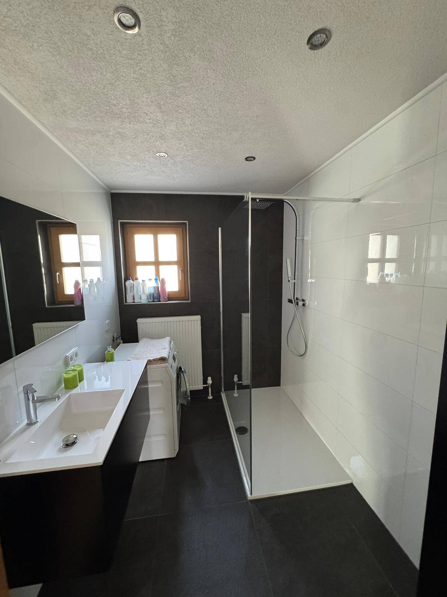 Modernes Badezimmer mit ebenerdiger Dusche, Doppelwaschbecken und einem Fenster für Tageslicht.