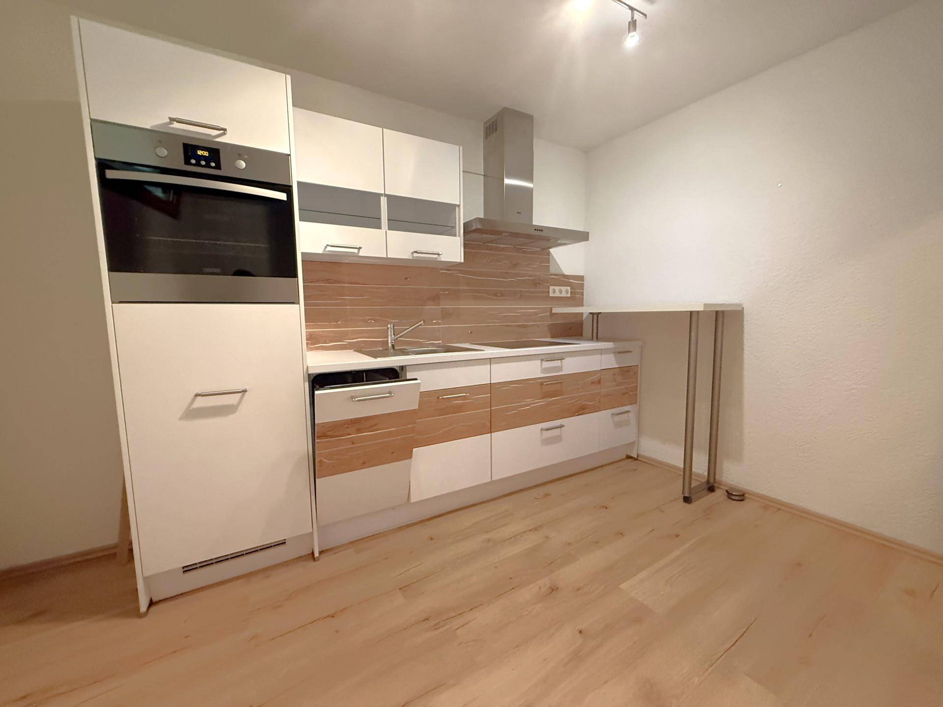 Moderne Küchenzeile mit weißen und holzfarbenen Schränken, Einbaugeräten und Frühstücksbar.