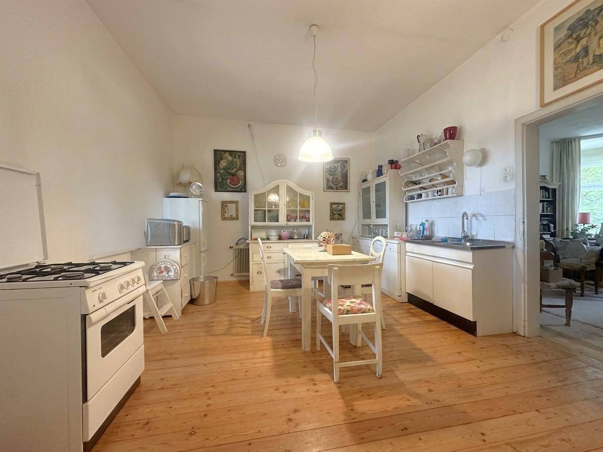 Geräumige Küche mit Holzdielenboden, Esstisch und traditionellen Einbaumöbeln.