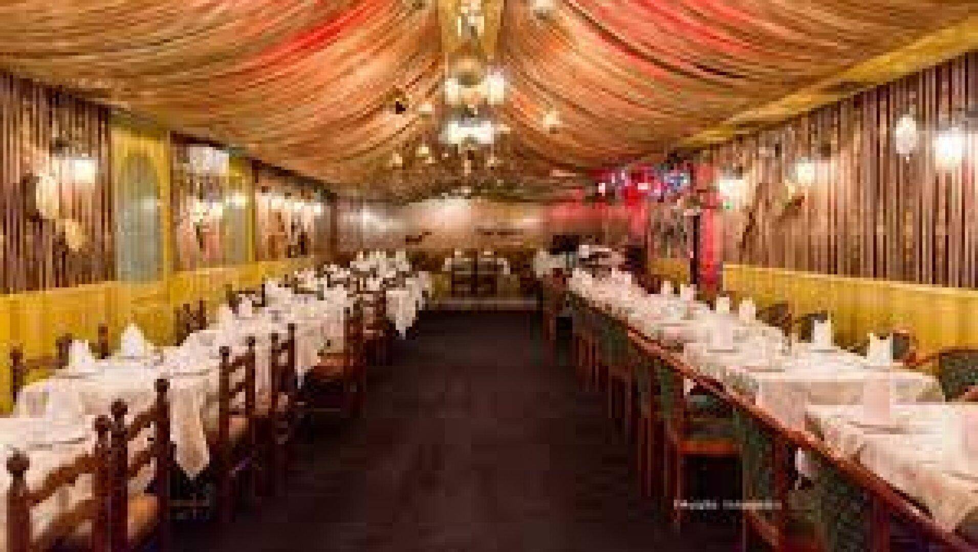 Großer Restaurant-Speisesaal mit festlich gedeckten Tischen und drapierter Deckenverkleidung.