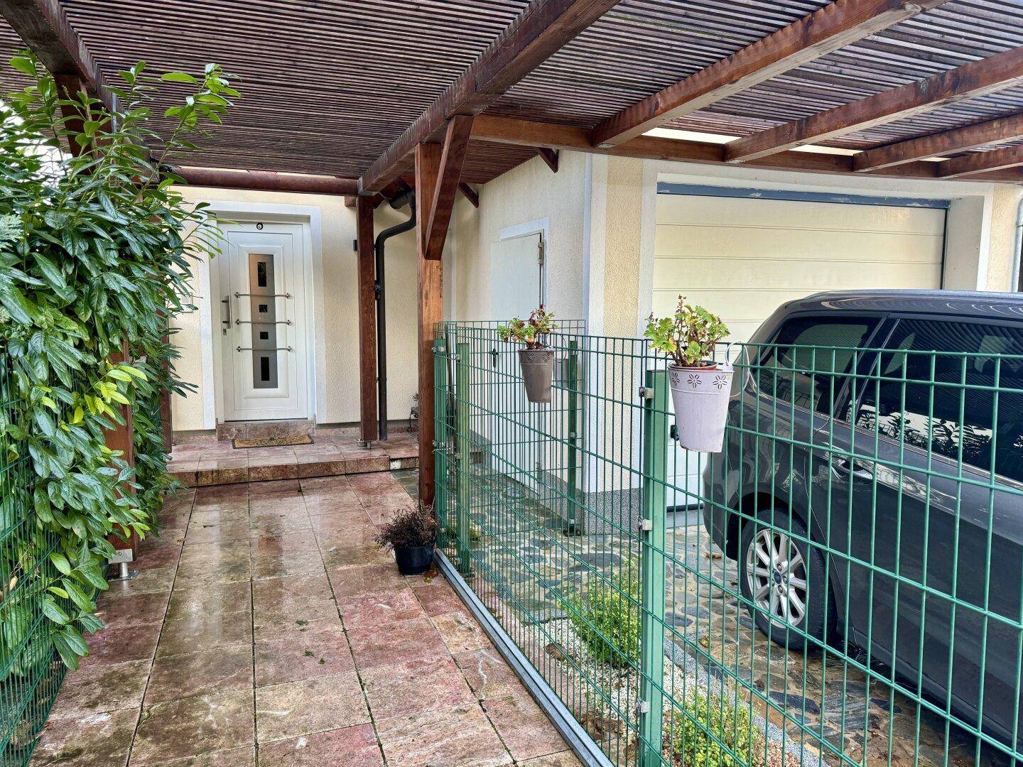 Eingangsbereich des Hauses mit überdachtem Carport und gepflastertem Zugang.
