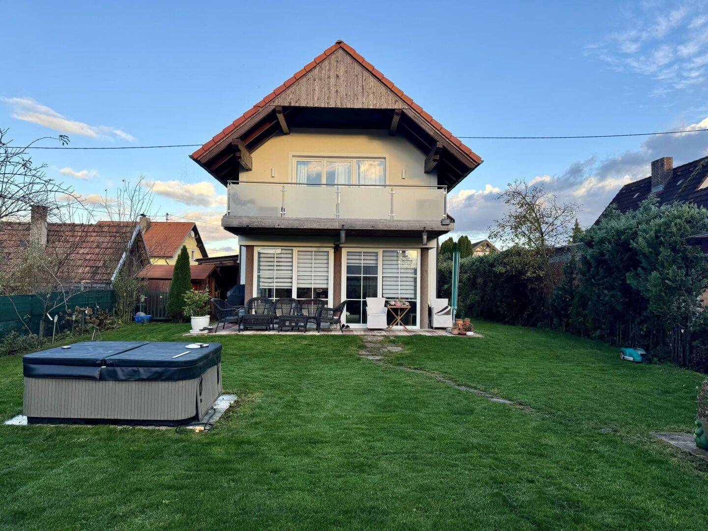 Rückansicht des Hauses mit großem Garten, Rasenfläche und einem Whirlpool.