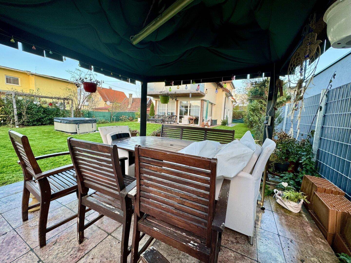 Überdachte Terrasse mit Holztisch und Stühlen, ideal für Mahlzeiten im Freien.