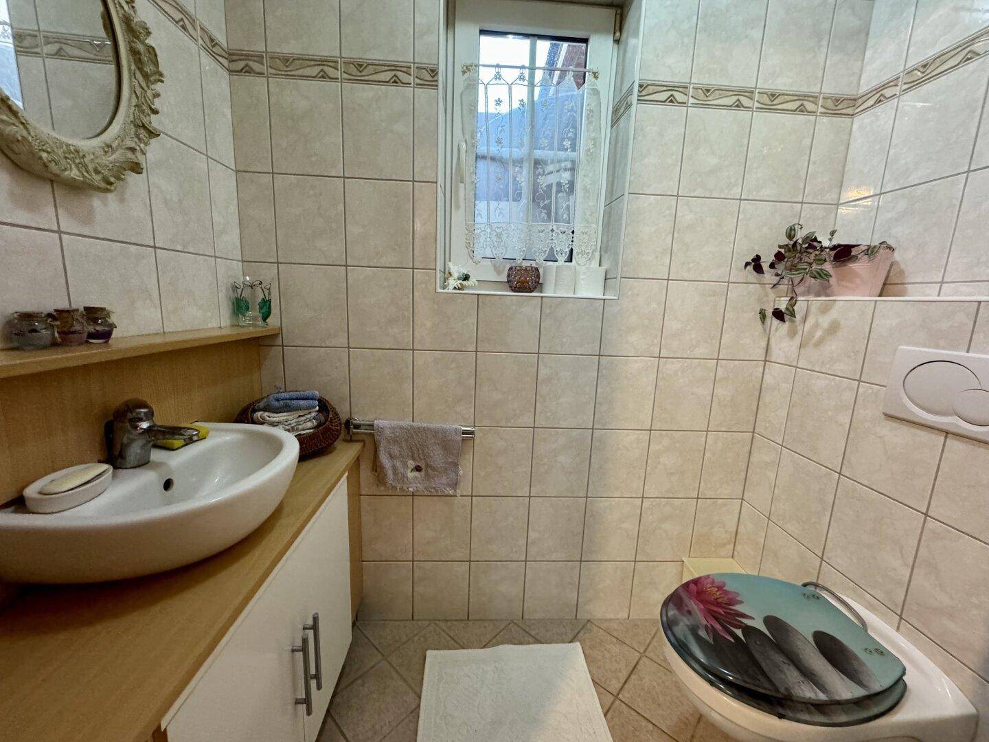 Kleines Gäste-WC mit Waschbecken, Toilette und hellen Fliesen.