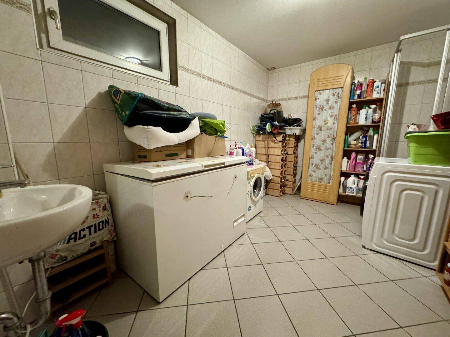 Hauswirtschaftsraum im Keller mit Waschmaschine, Gefriertruhe und Waschbecken.
