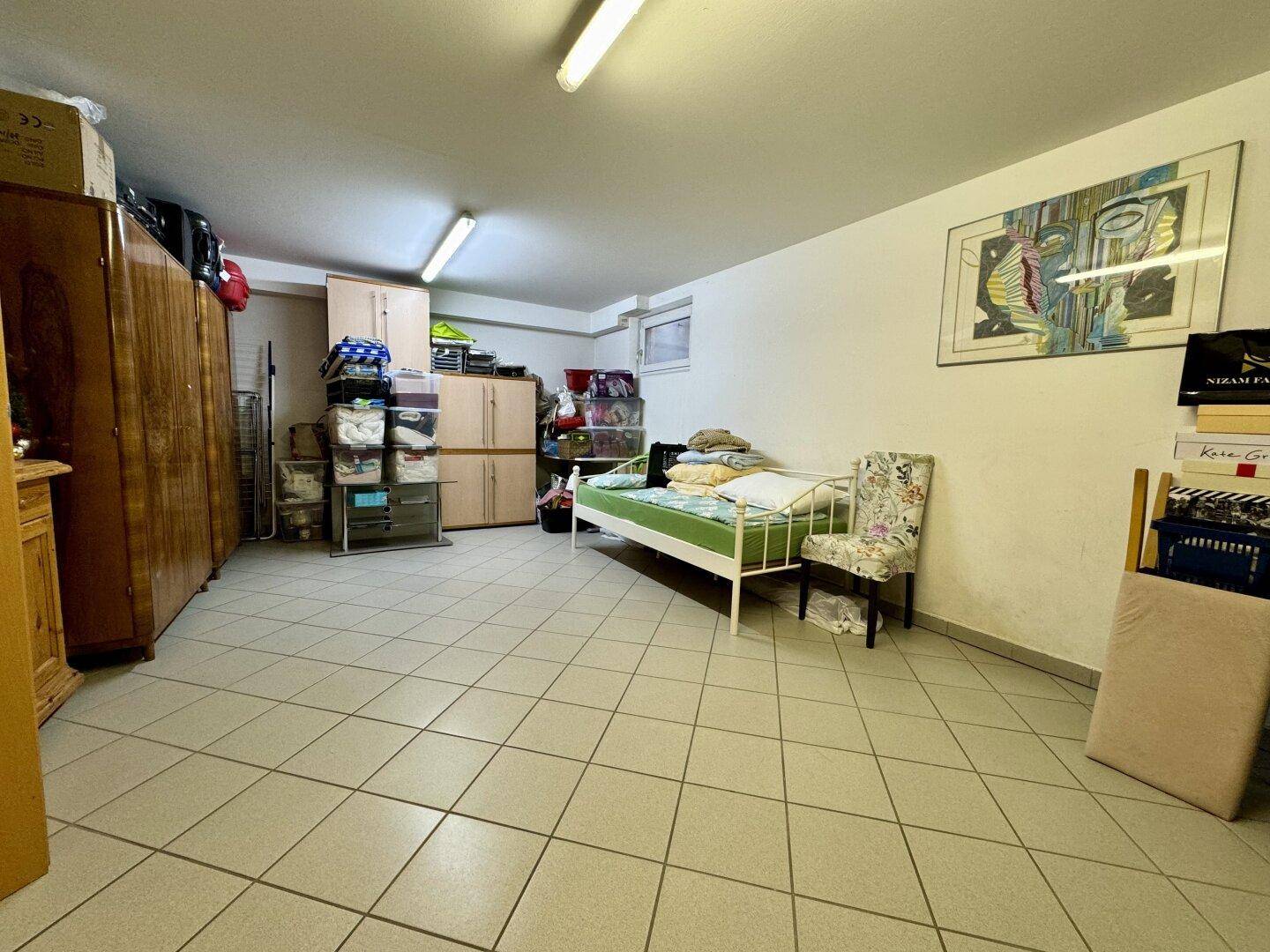 Geräumiger Kellerraum mit Fliesenboden, als Lager- und Gästezimmer genutzt.