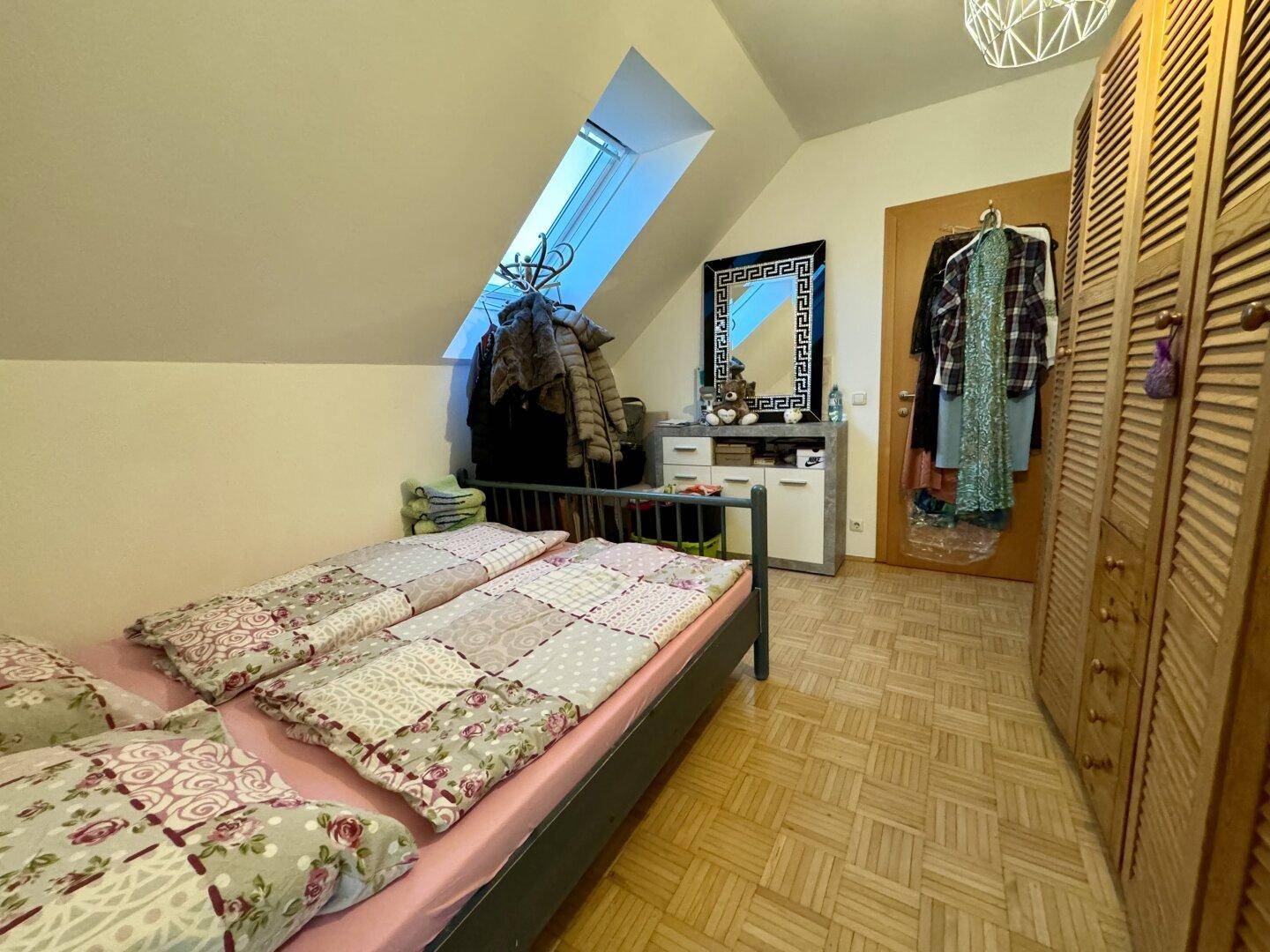 Gemütliches Schlafzimmer im Dachgeschoss mit Dachfenster und Parkettboden.