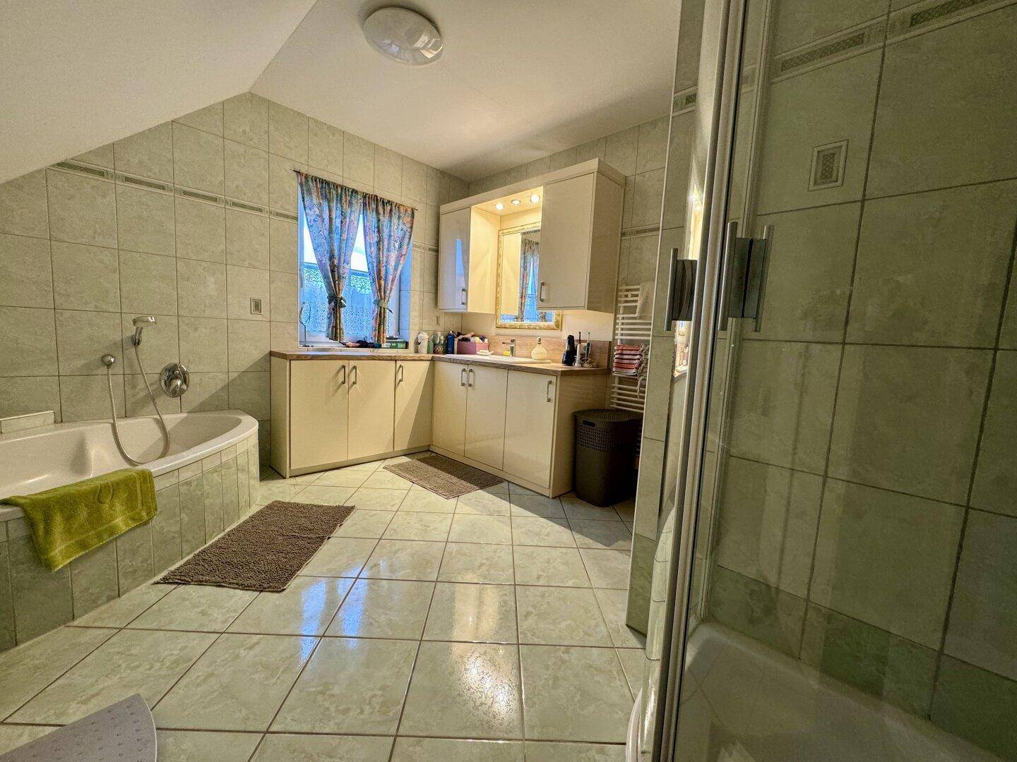 Geräumiges Badezimmer mit Eckbadewanne, Dusche und hellen Fliesen.