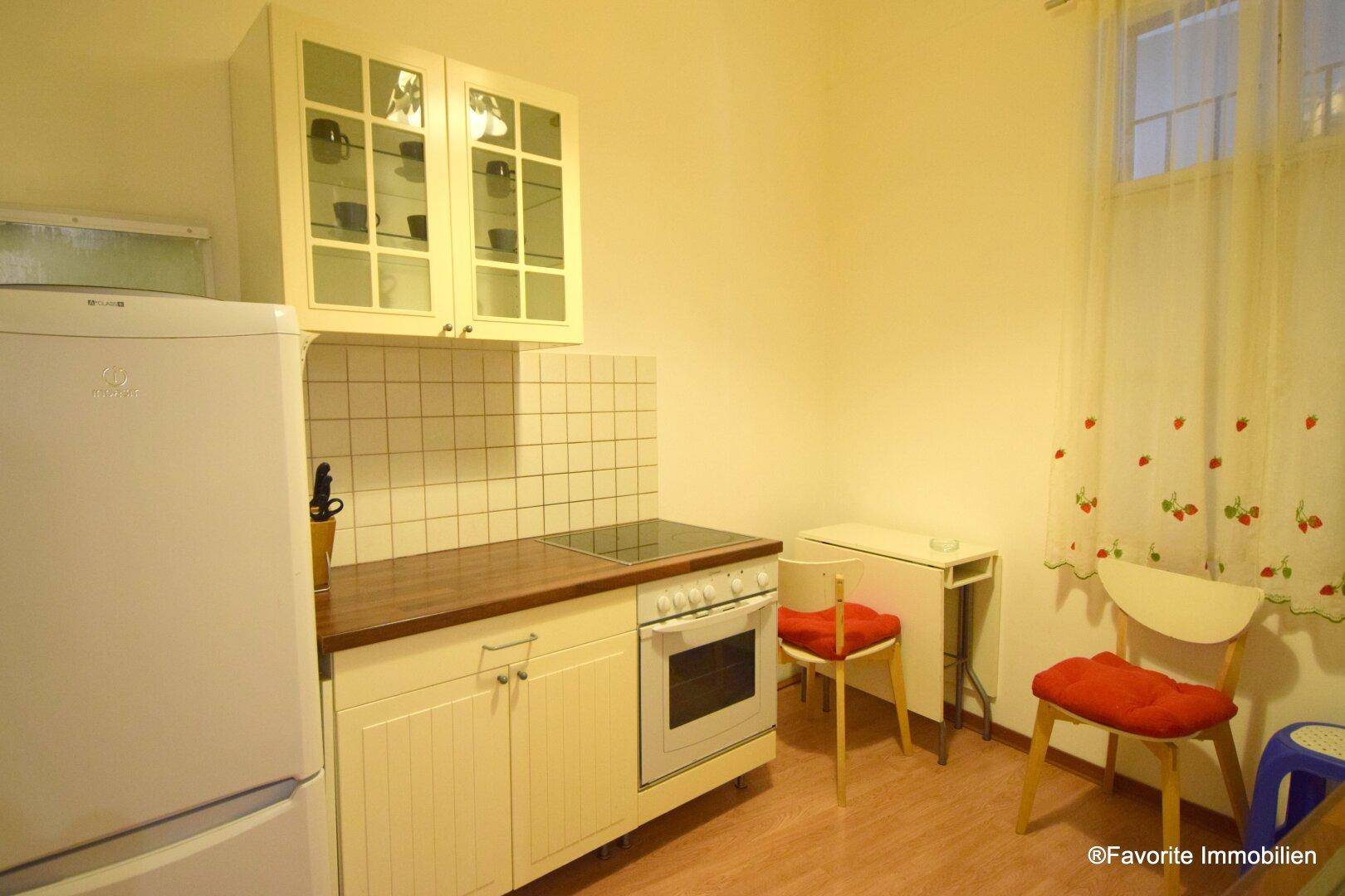 Kleine Küche mit weißer Einbauküche, Herd und Kühlschrank.