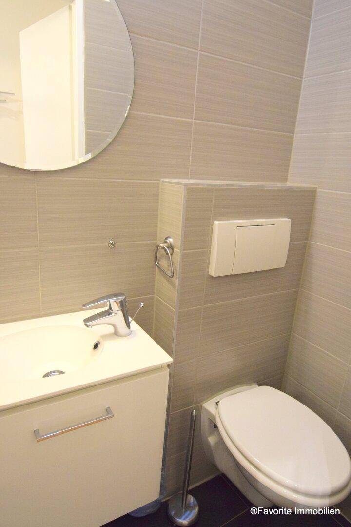 Modernes Badezimmer mit Wand-WC, Waschbecken und grauen Fliesen.