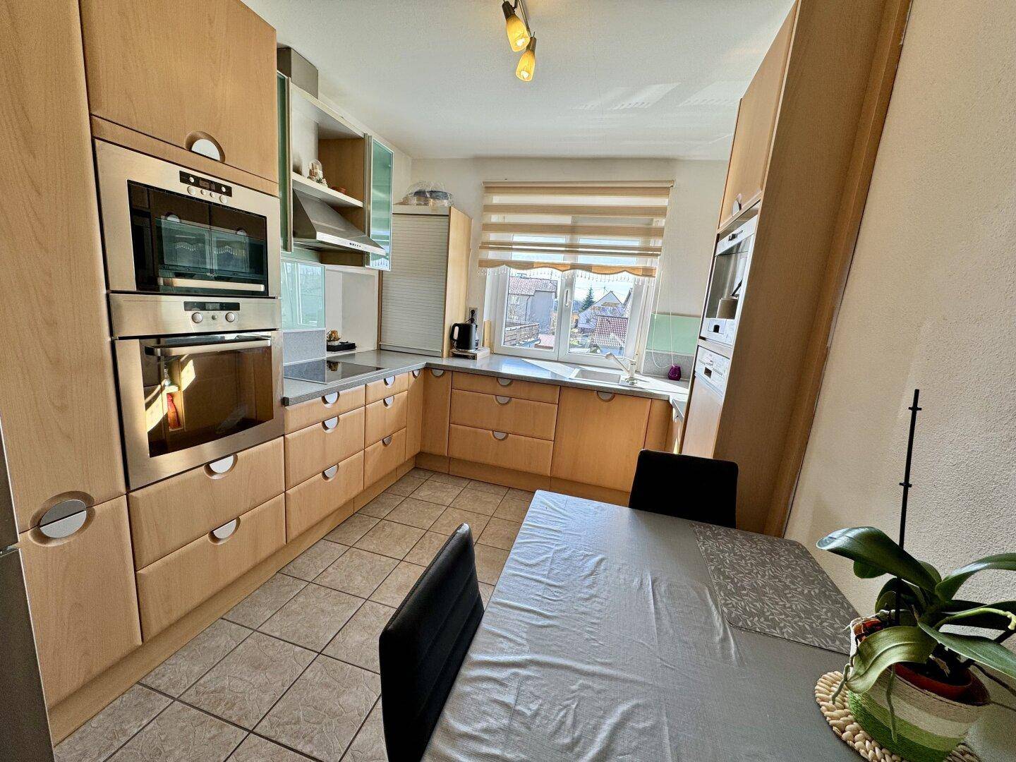 Funktionale Küche mit Holzfronten, Einbaugeräten und Essbereich für die Familie.