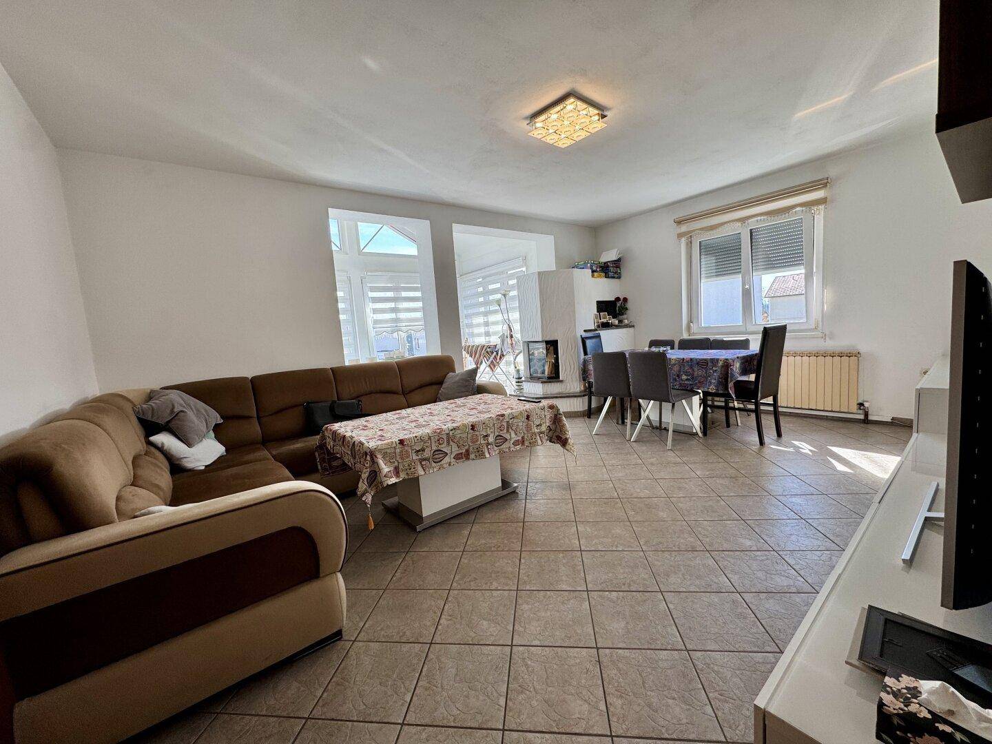 Geräumiger Wohn-Essbereich mit Fliesenboden, gemütlichem Sofa und Esstisch für die Familie.