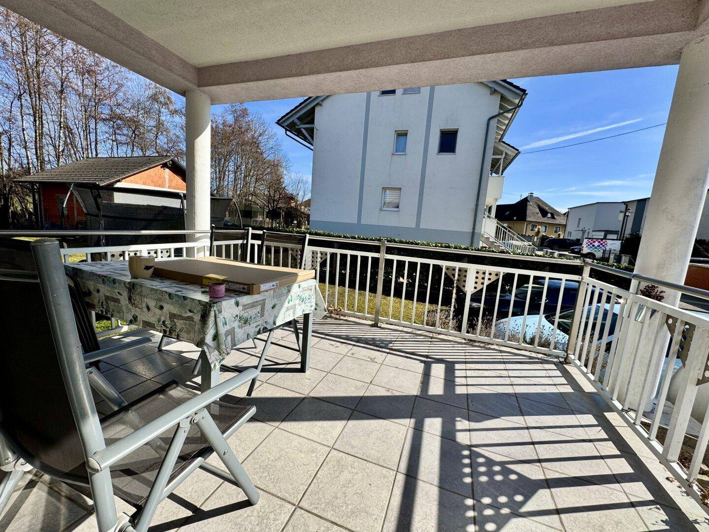 Überdachter Balkon mit Fliesenboden und Gartenmöbeln, ideal zum Entspannen im Freien.