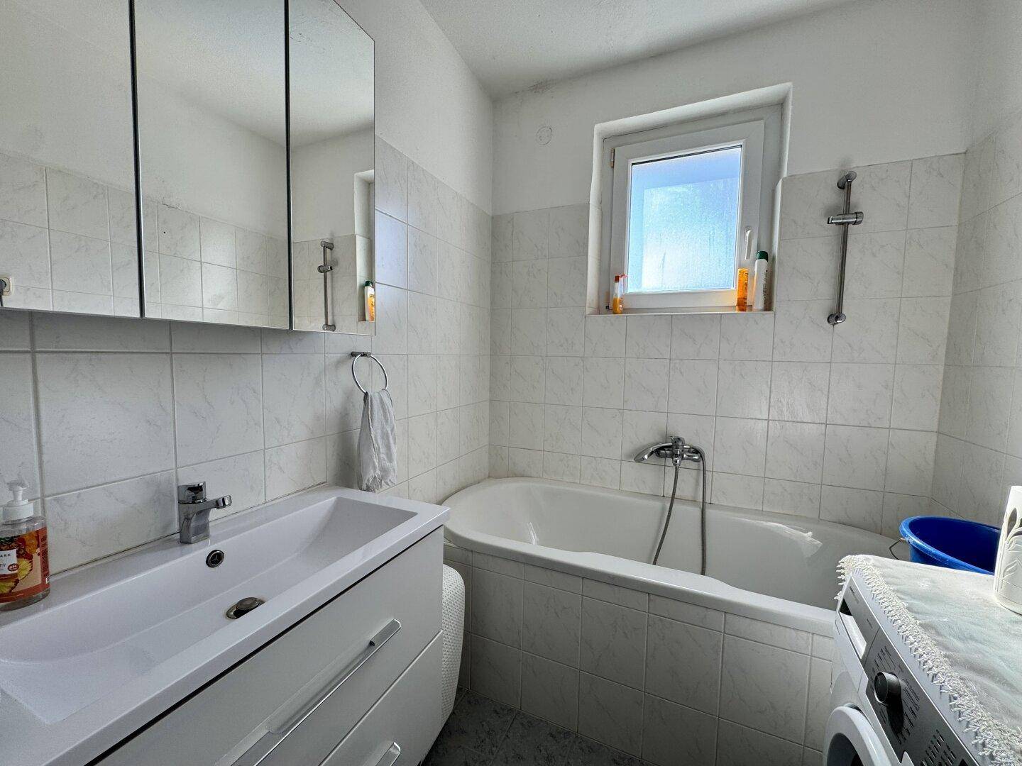 Helles Badezimmer mit Badewanne, modernem Waschbecken und Spiegelschrank.