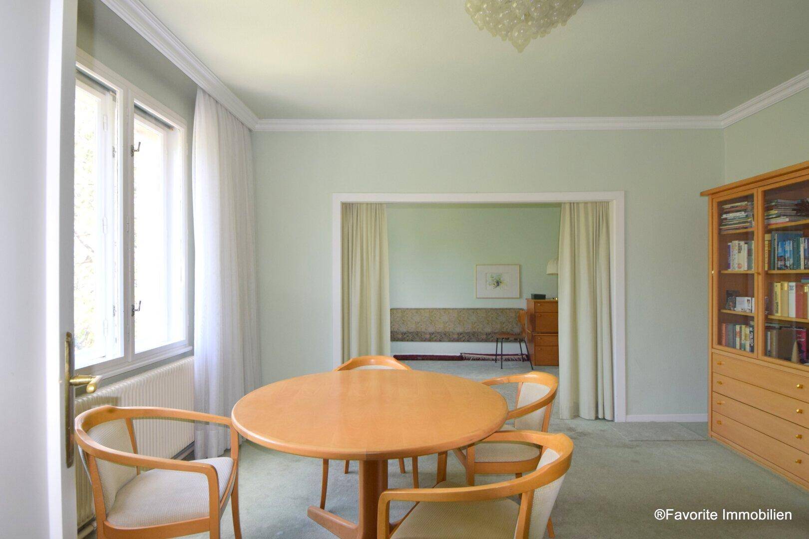 Wohn- und Essbereich mit Esstisch, Teppichboden und Durchgang zu einem weiteren Zimmer.