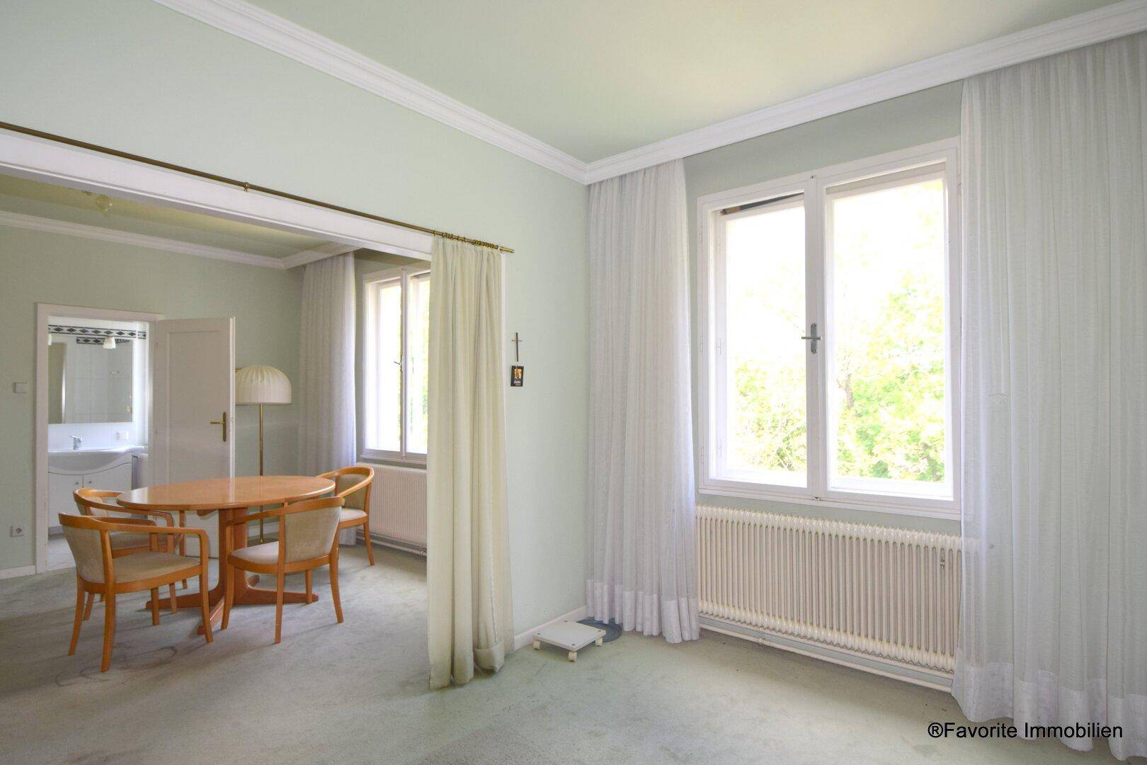 Geräumiges Wohn- und Esszimmer mit Teppichboden und hellen Fenstern zum Garten.