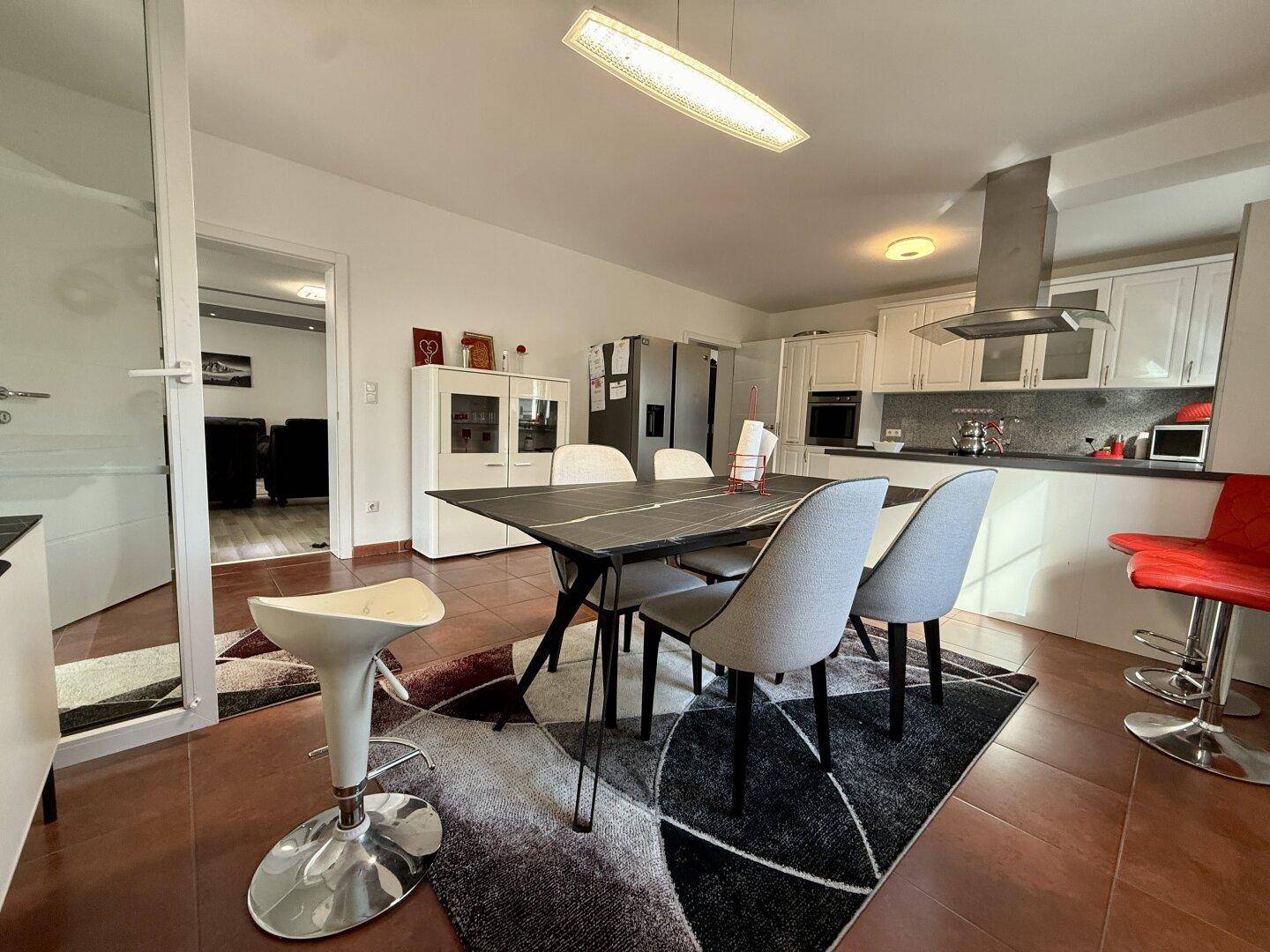 Moderne Wohnküche mit Esstisch, Barhockern und Blick in den angrenzenden Wohnbereich.