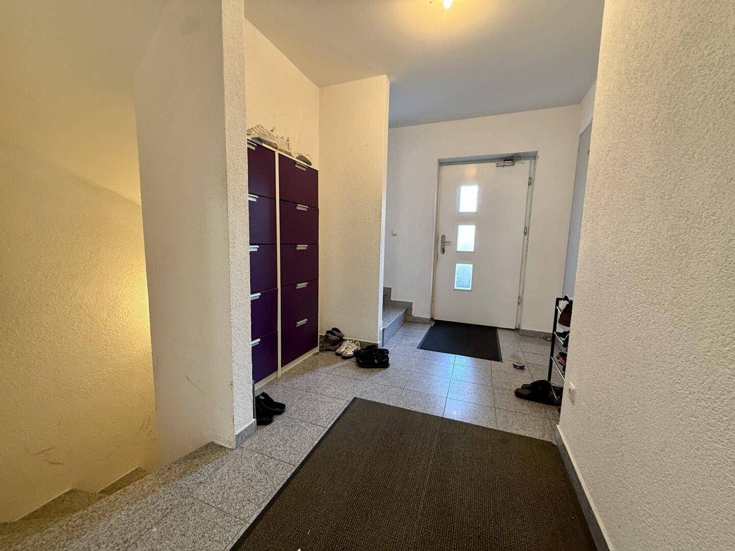 Eingangsbereich mit Fliesenboden, Garderobe und Treppenaufgang.